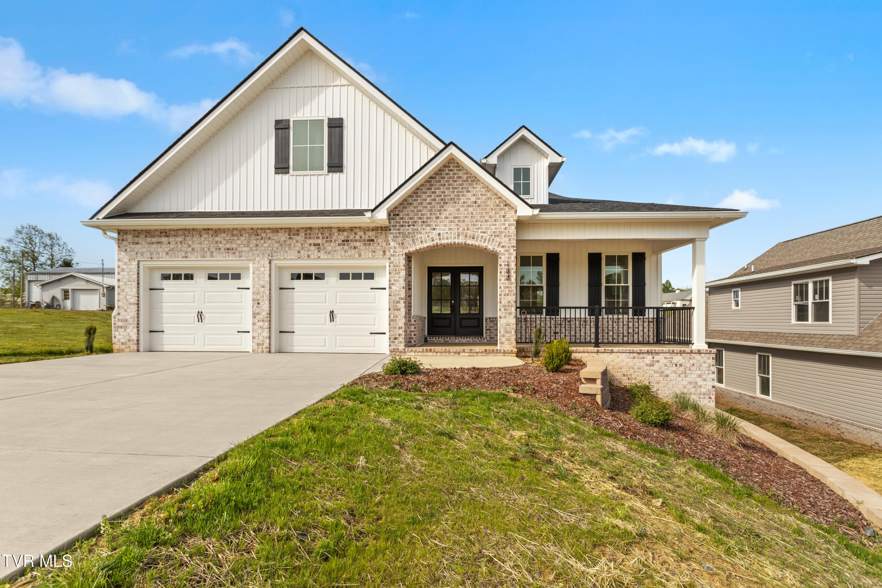 Two-story brick and white-sided home with a double garage and covered front porch.