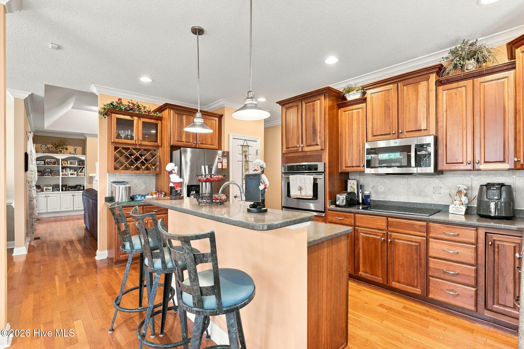 Kitchen with extensive wood cabinetry, stainless steel appliances, and a breakfast island with bar stools.