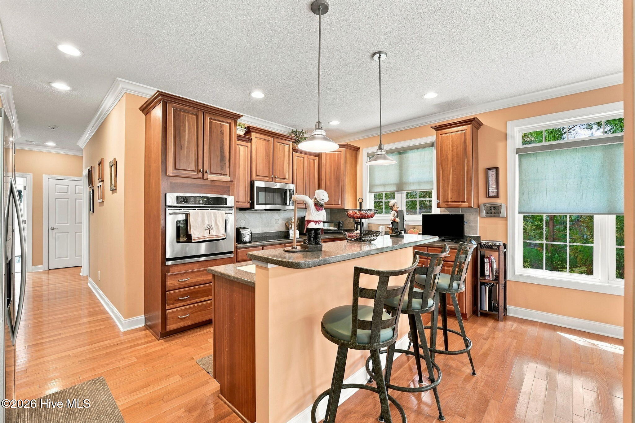 Kitchen with warm wood cabinets, stainless steel appliances, and a large island with bar seating.