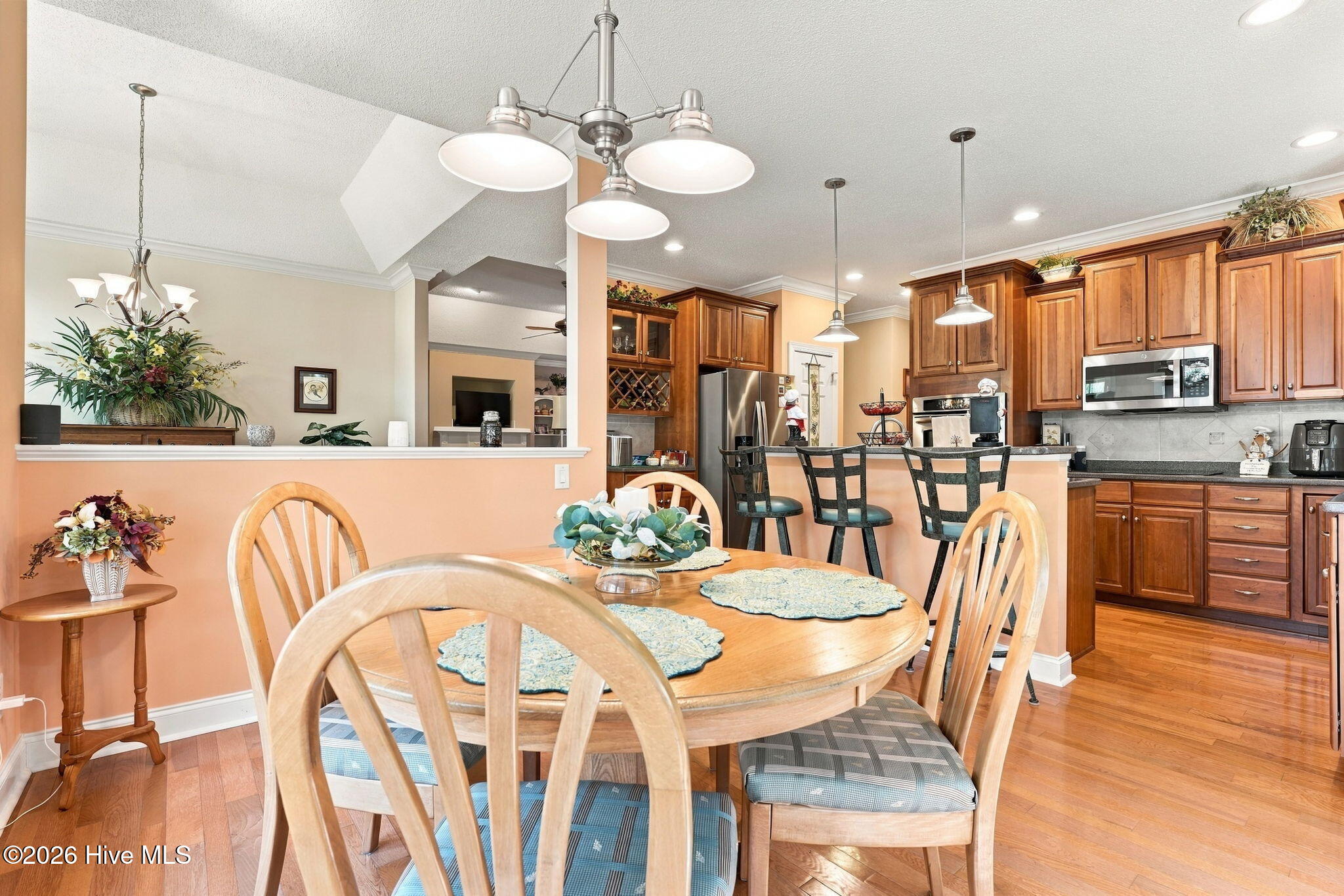 Dining area and kitchen with a wood table, cherry cabinets, breakfast bar, and stainless steel appliances.