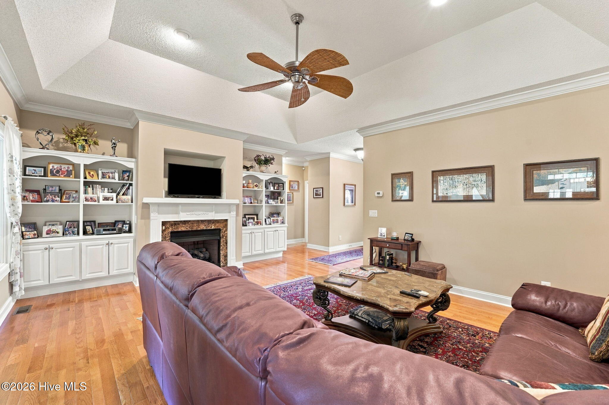 Living room with built-in shelving, fireplace, hardwood floors, and leather seating.