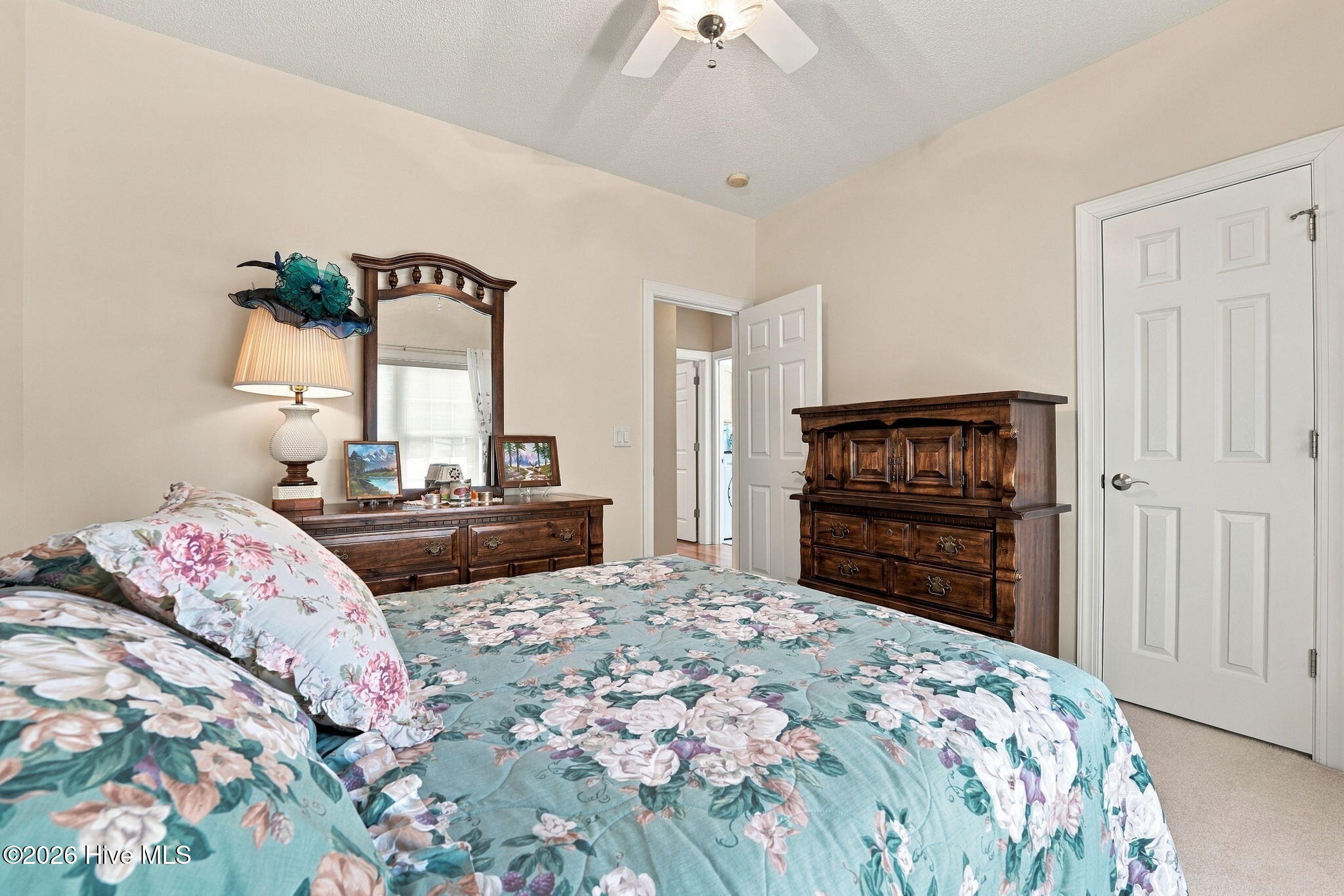 Furnished bedroom with teal floral bedding, dark wood dressers, and a matching mirror.