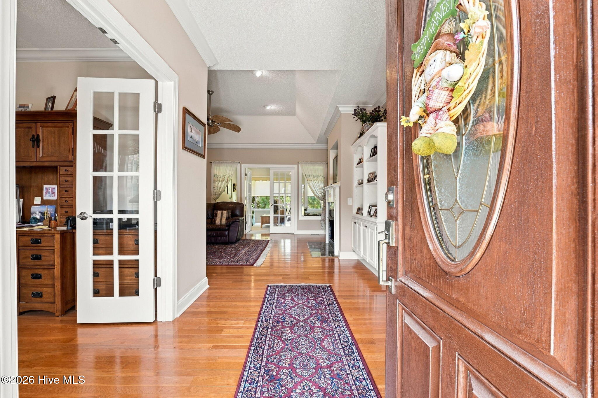 Furnished entryway with hardwood floors, a patterned runner, and an open front door with a harvest wreath.