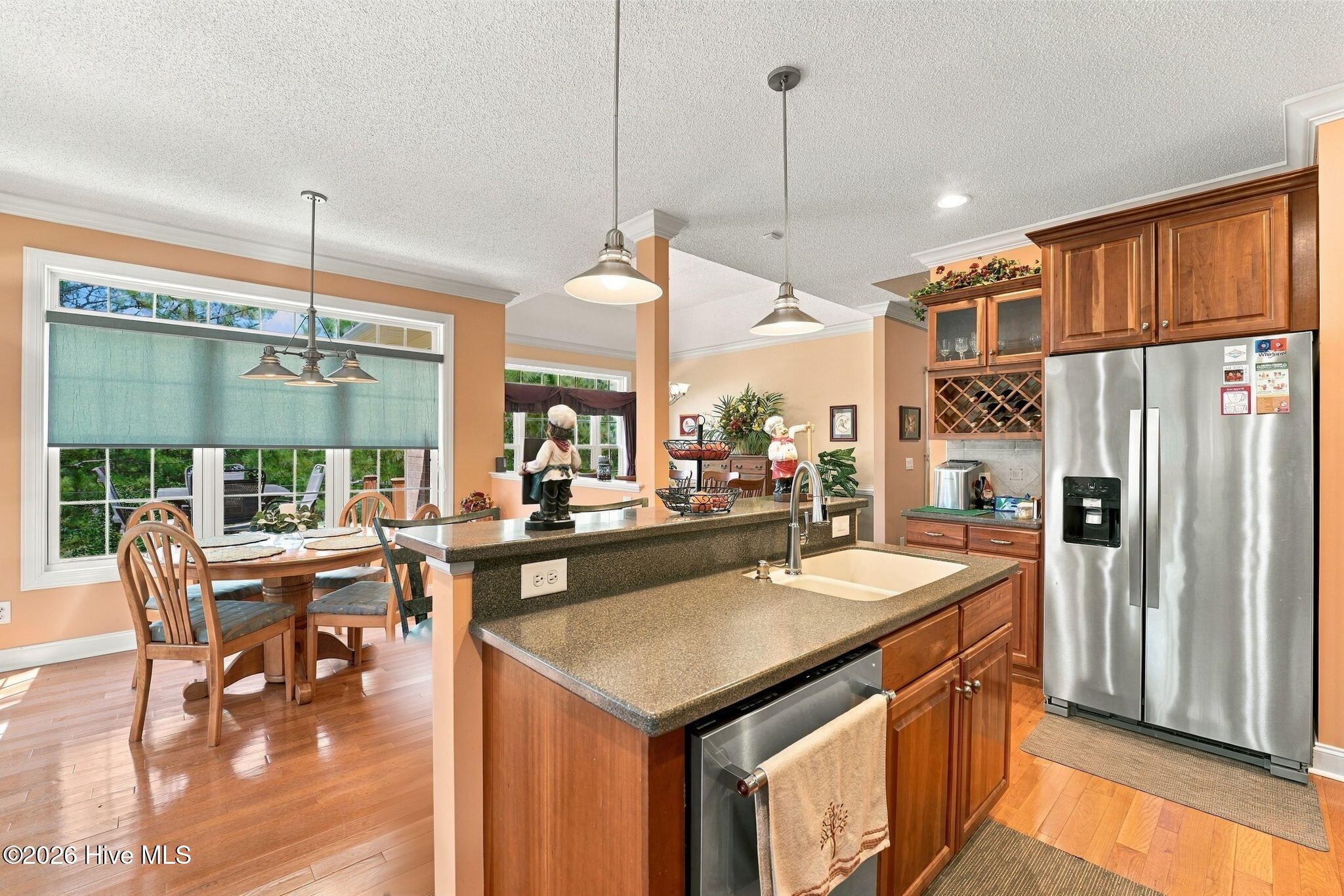 Kitchen with granite island, stainless steel appliances, warm wood cabinetry, and an adjoining dining area.