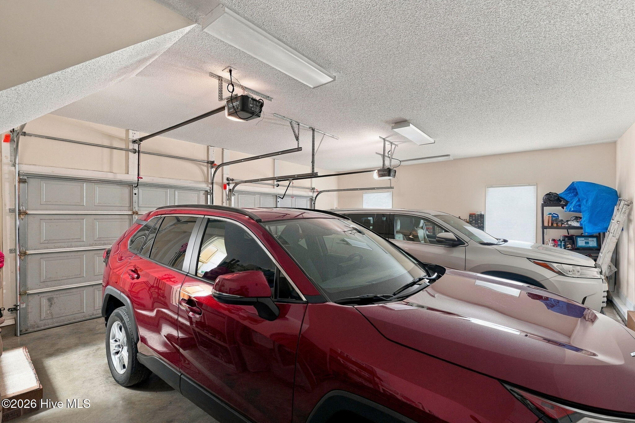 Two-car garage with a red SUV and white vehicle parked inside.