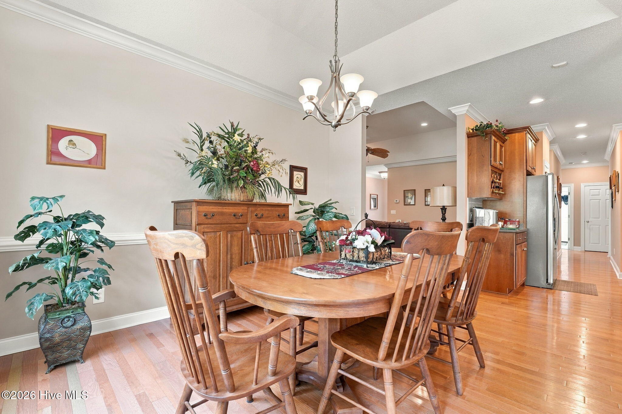 Dining room with a round wooden table and chairs beside an open kitchen with wood cabinets.