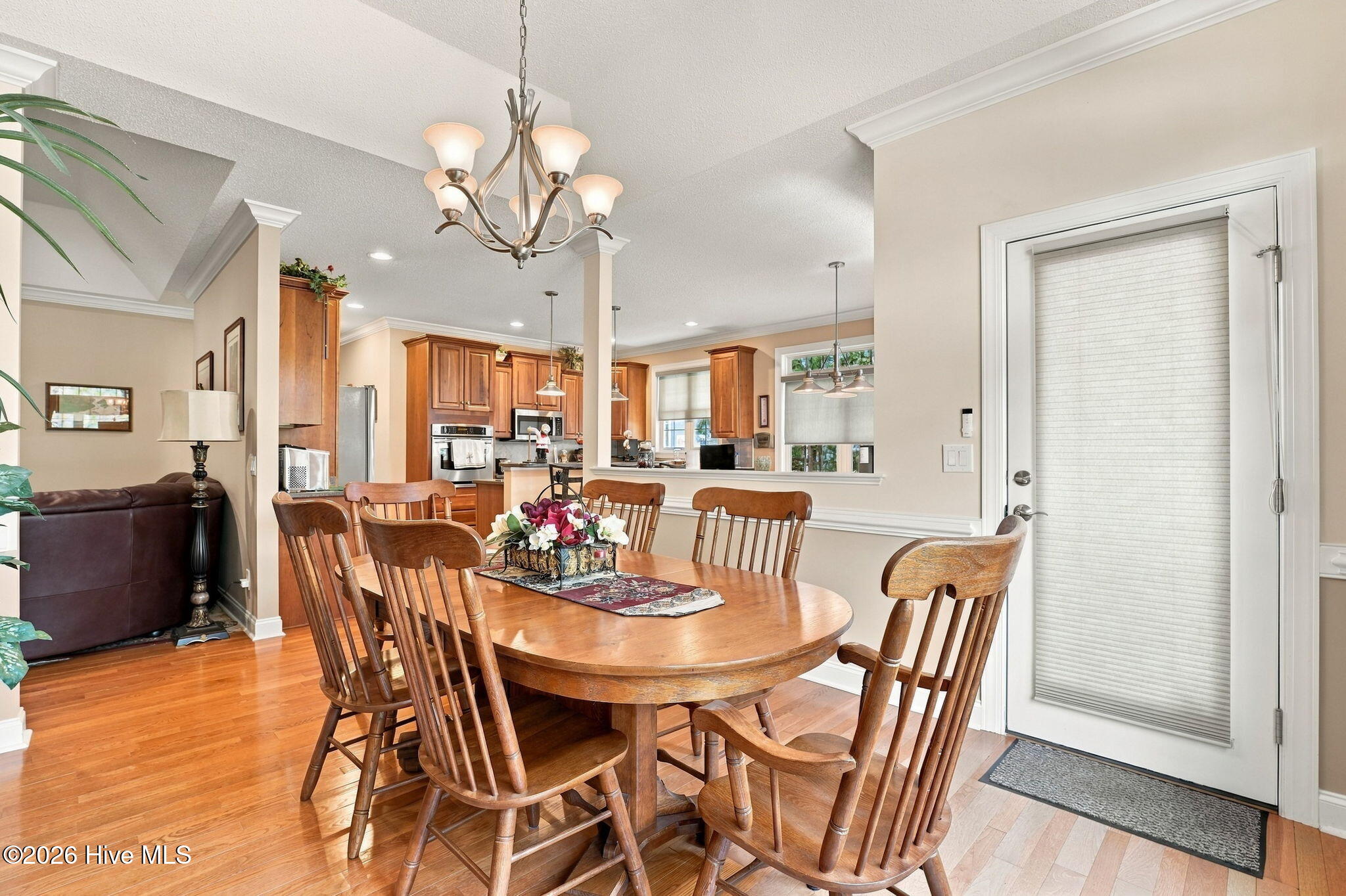 Dining area with a wooden table and chandelier, opening to the kitchen and living room.