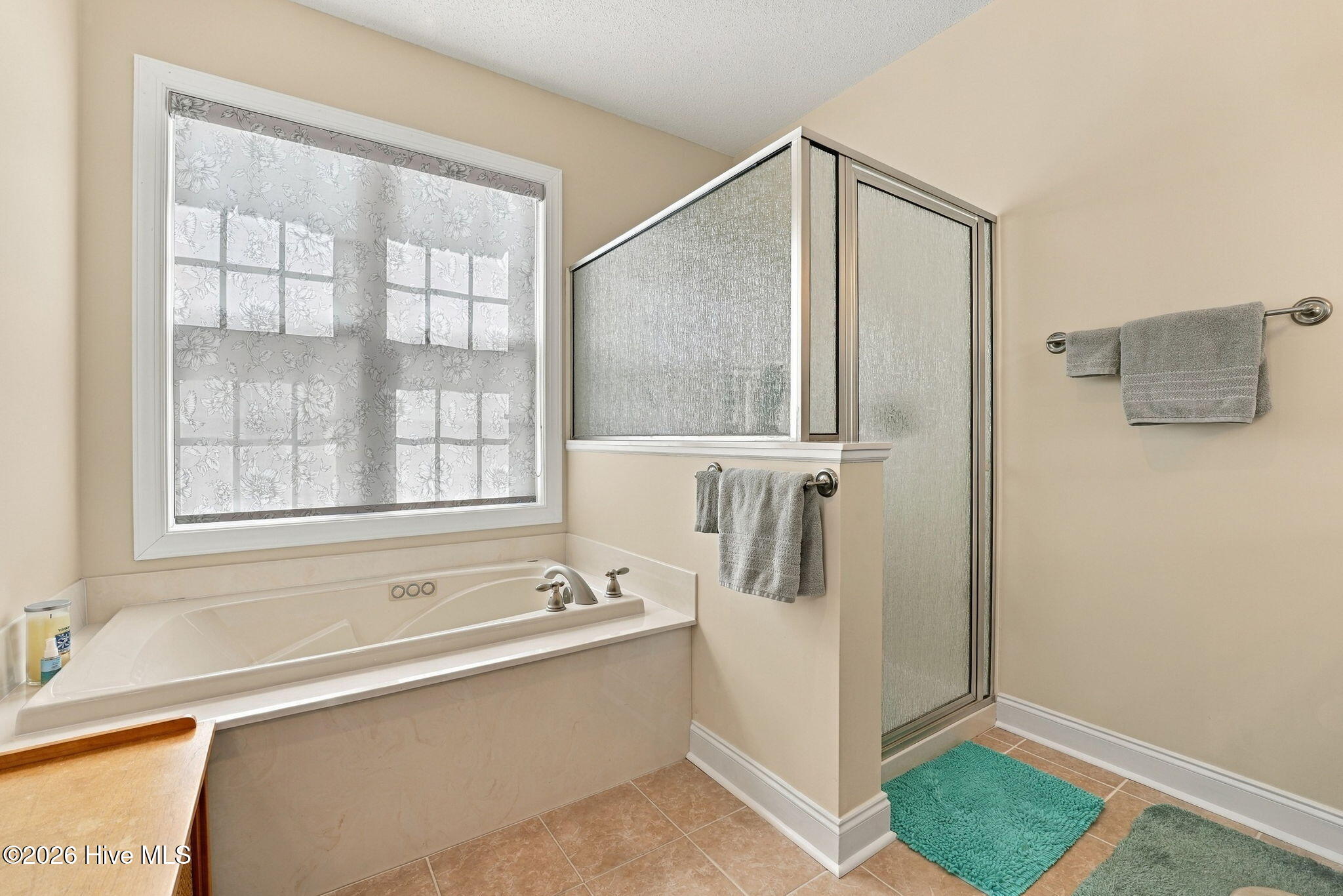 Bathroom with a soaking tub beneath a large window and a glass-enclosed shower.