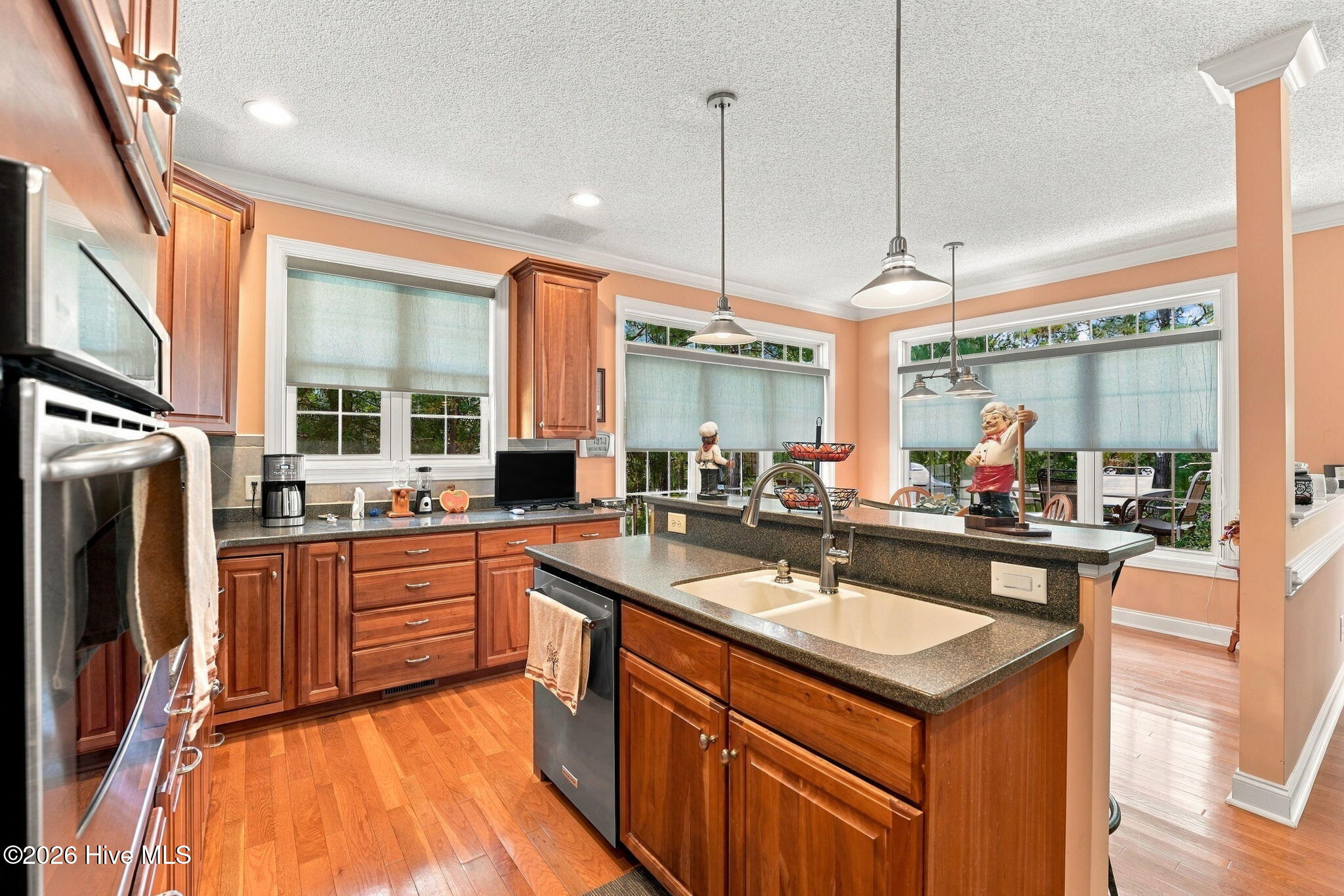 Kitchen with warm wood cabinetry, hardwood floors, and a large island with a double sink.
