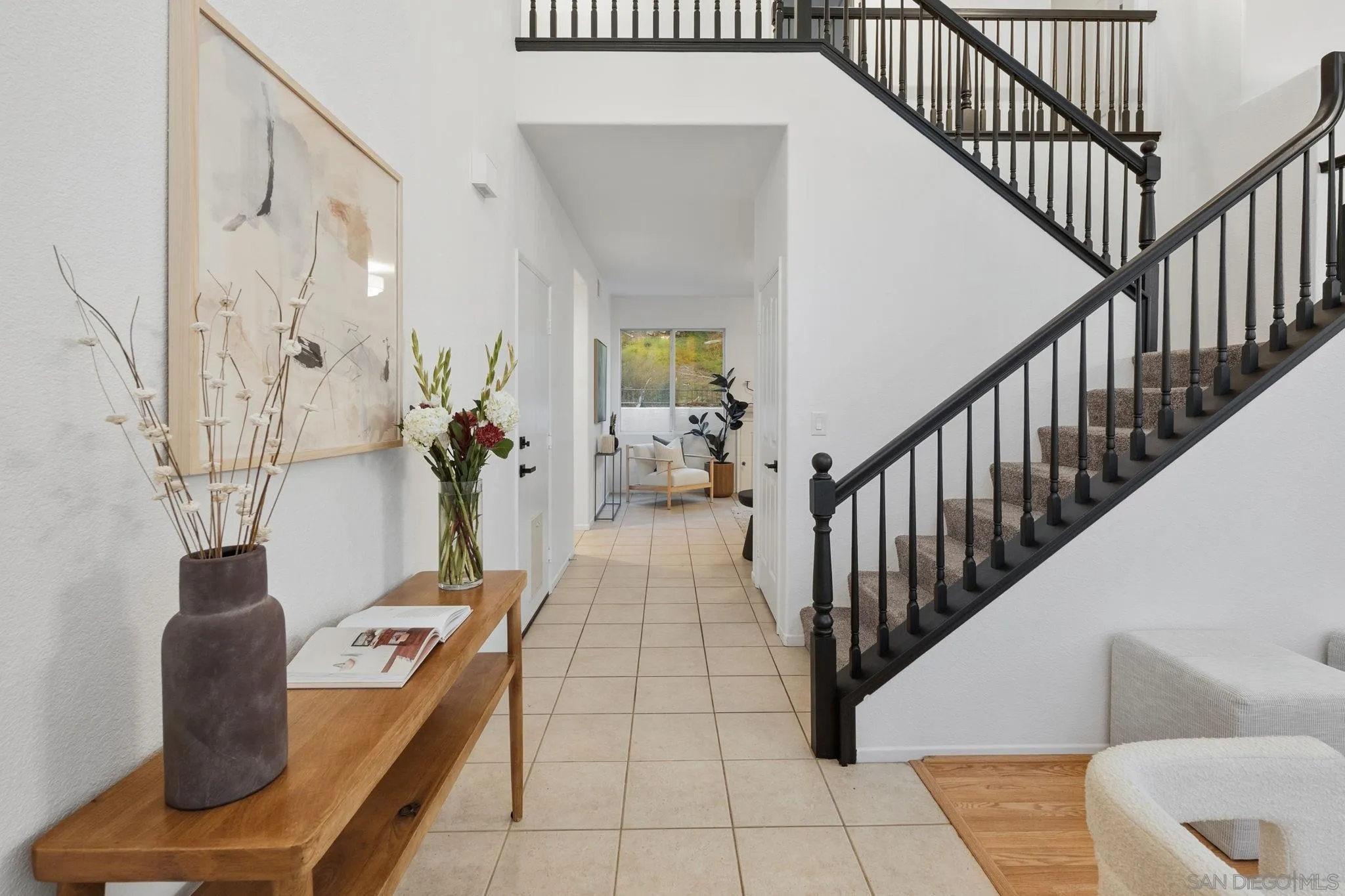Furnished entry hall with a black-railed staircase and a flower-decorated console table.