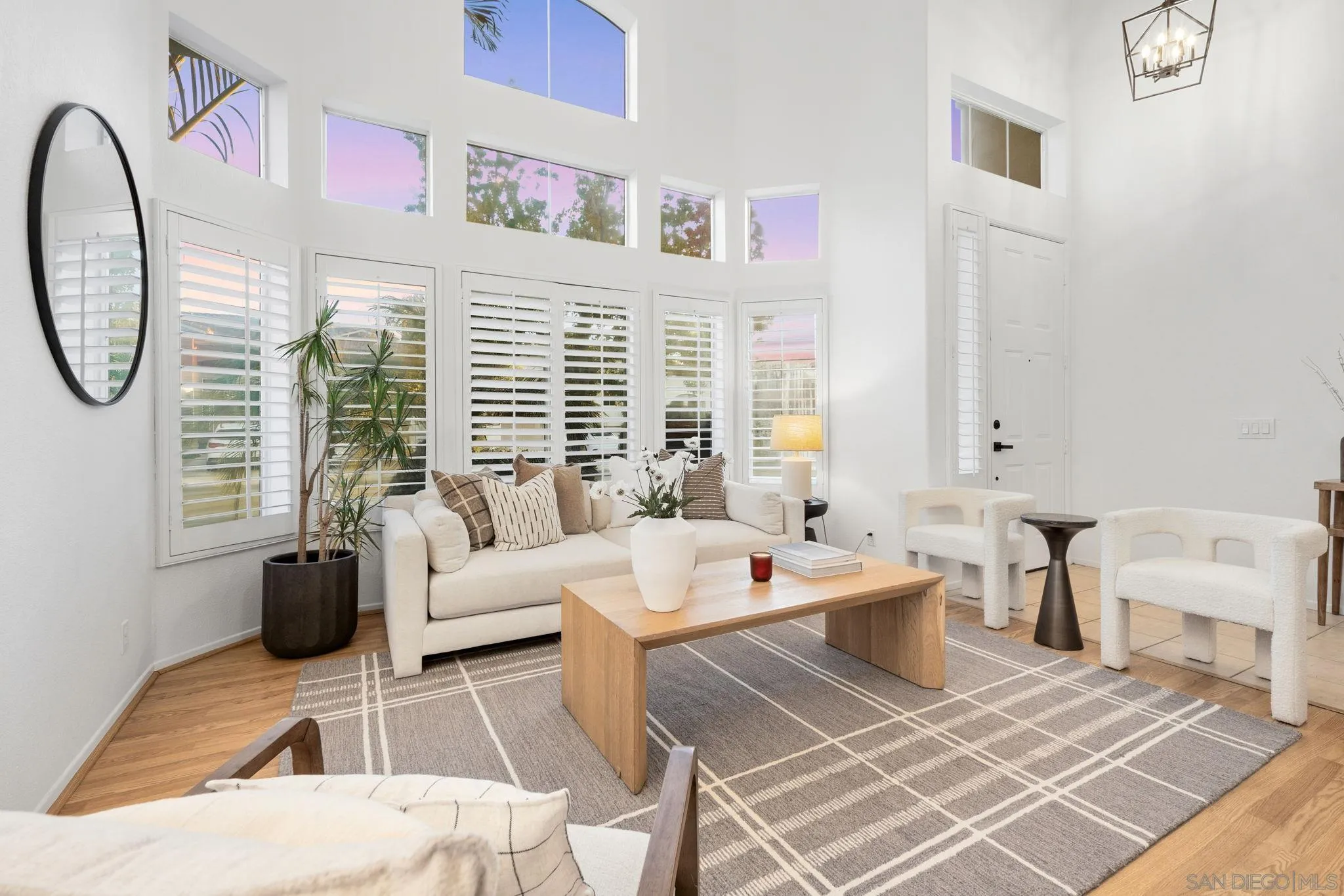 Bright living room with plantation-shuttered windows, a white sofa, and a wood coffee table.