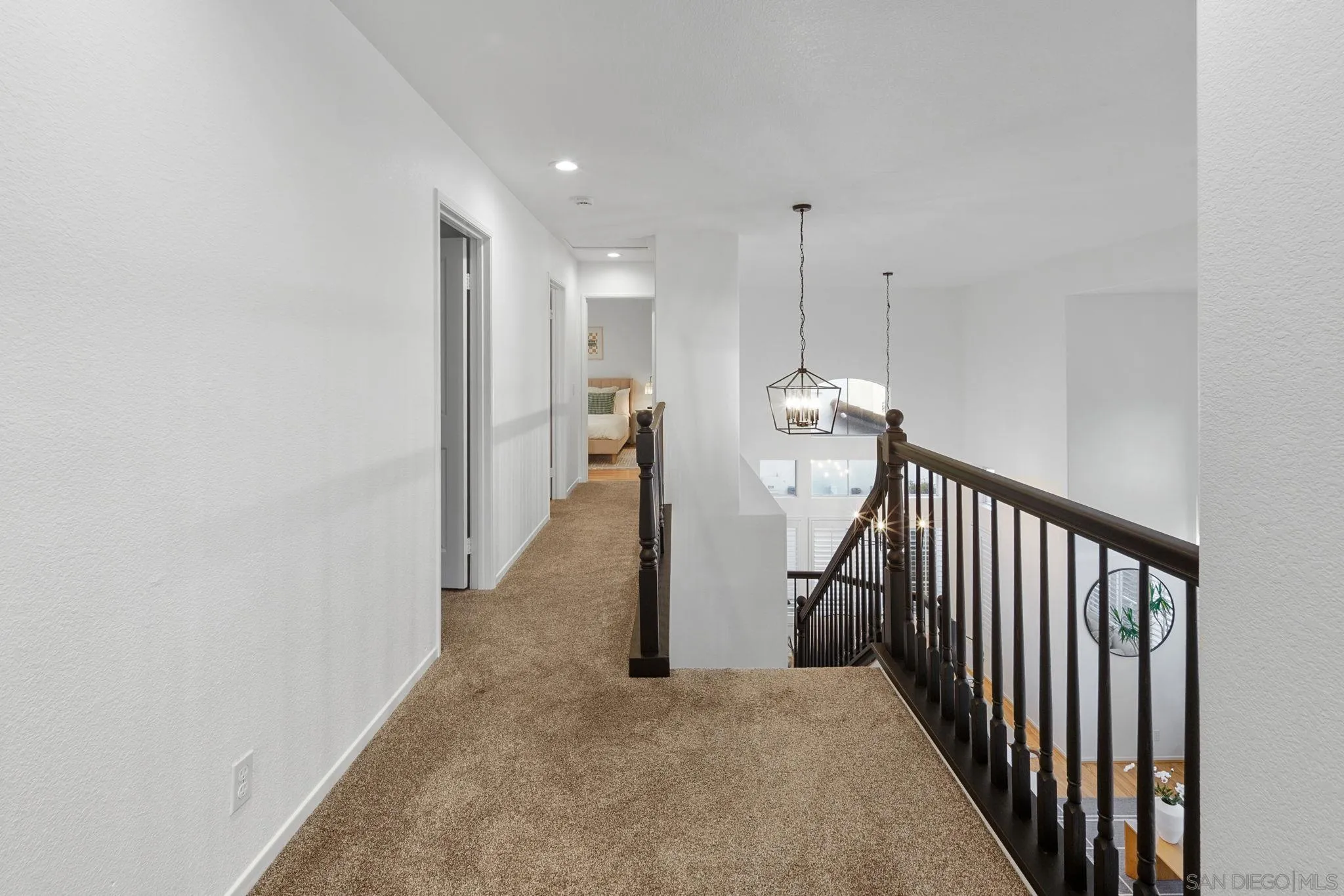 Carpeted upstairs landing with dark wood railing and lantern lights overlooking the stairwell.