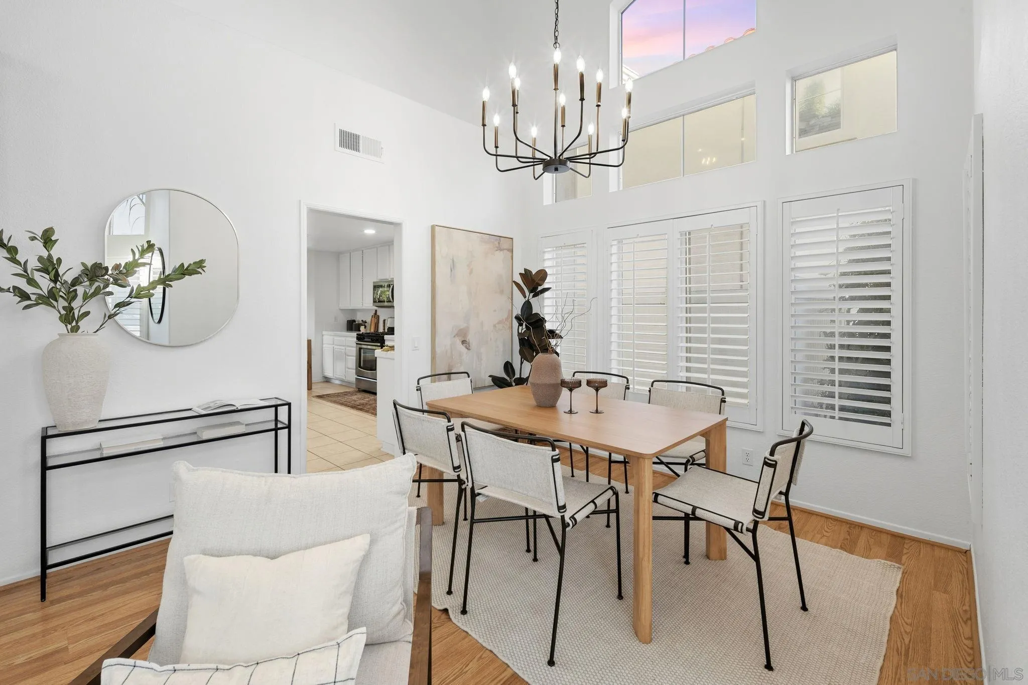 Dining room with a wooden table, black chandelier, and white plantation shutters.