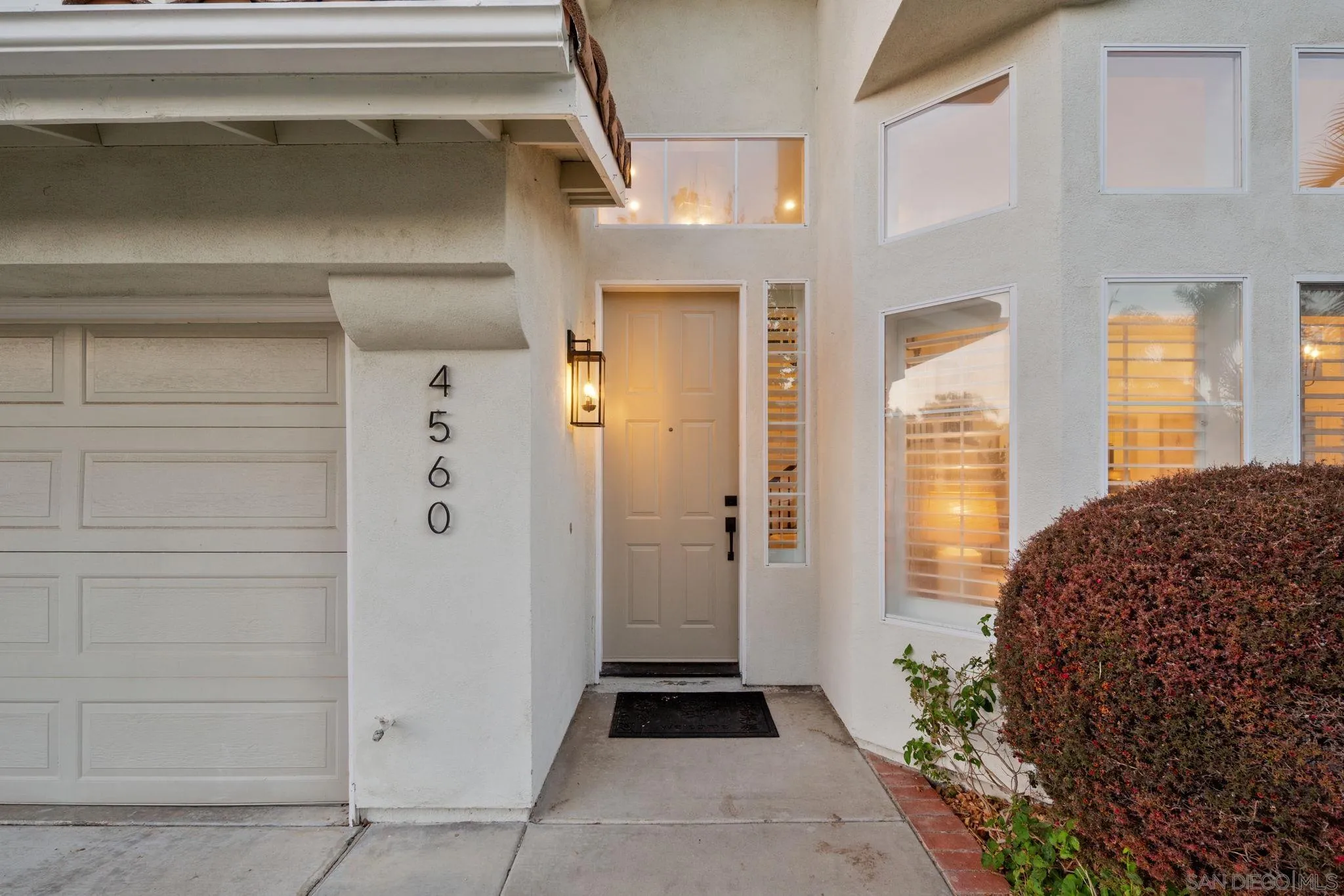 Home entrance with paneled garage door, illuminated lantern, and house number 4560.