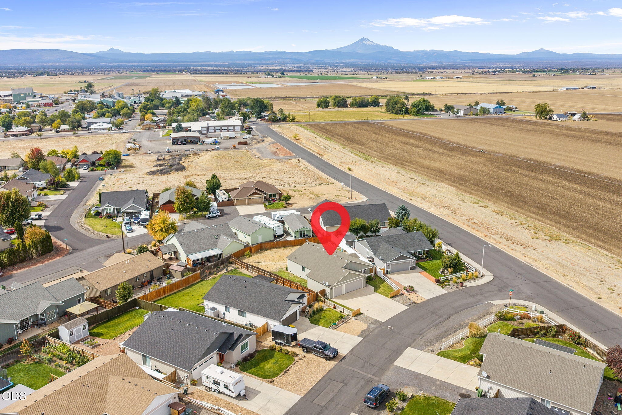 Aerial view of the marked home among neighborhood streets, fields, and distant mountains.