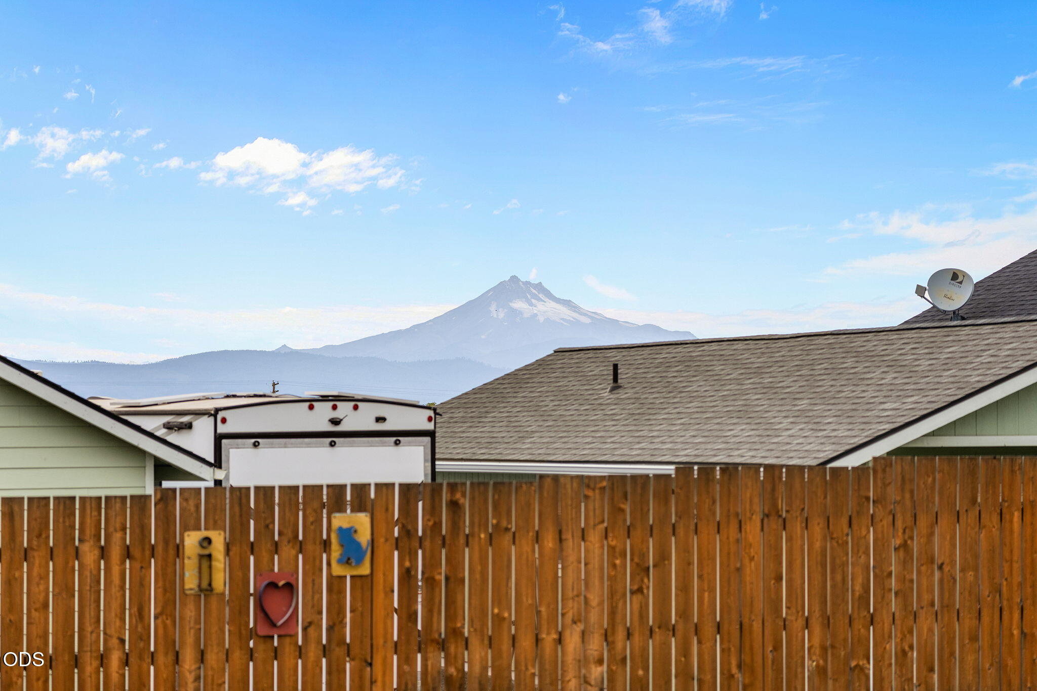 Mountain view beyond neighboring rooftops and a wooden privacy fence.