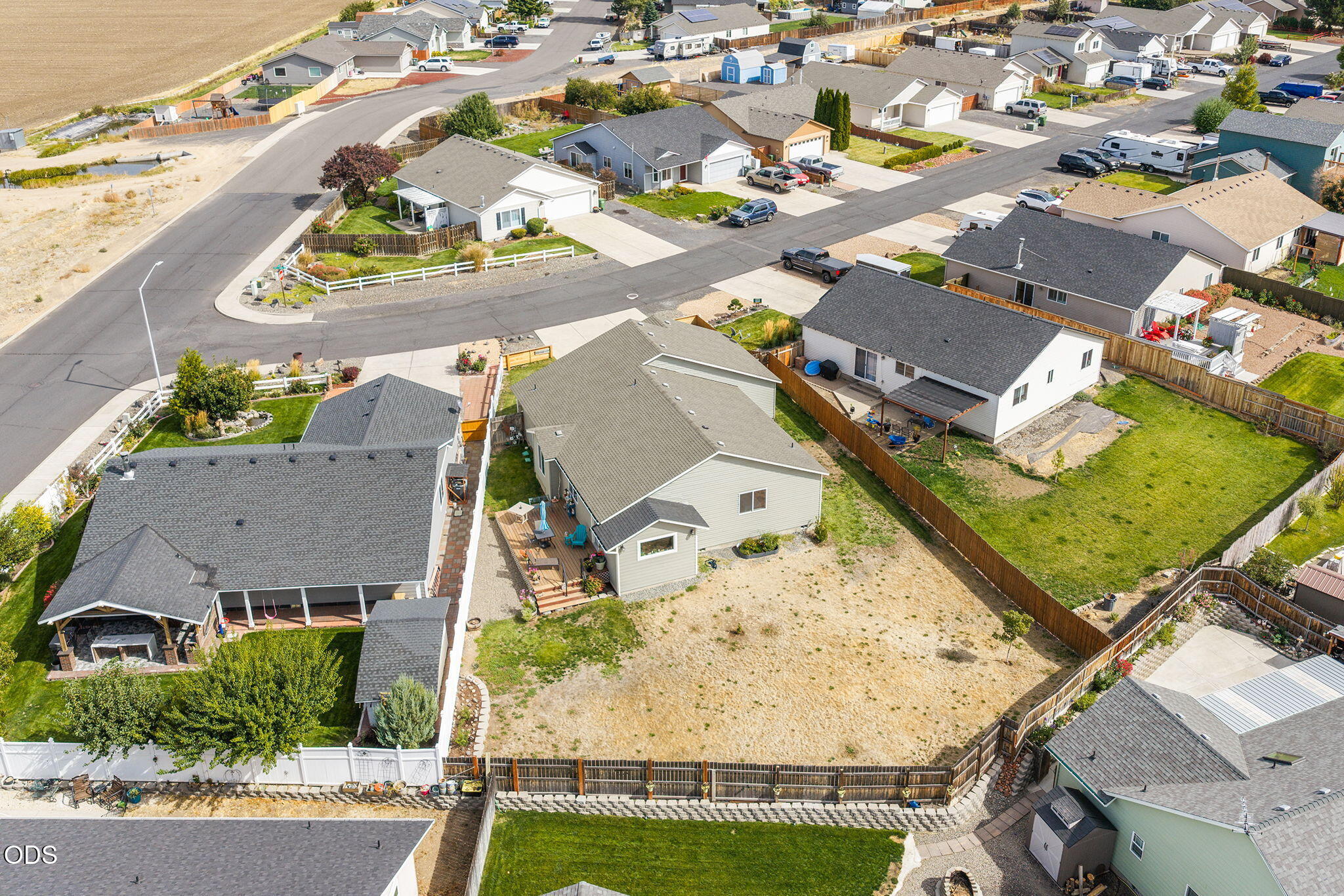 Aerial view of a home with a large fenced backyard and deck, surrounded by neighborhood streets and houses.
