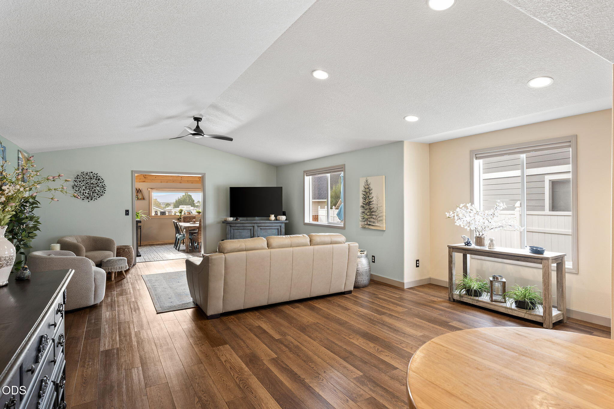 Staged living room with a beige sofa, dark wood floors, and an open doorway to the dining area.