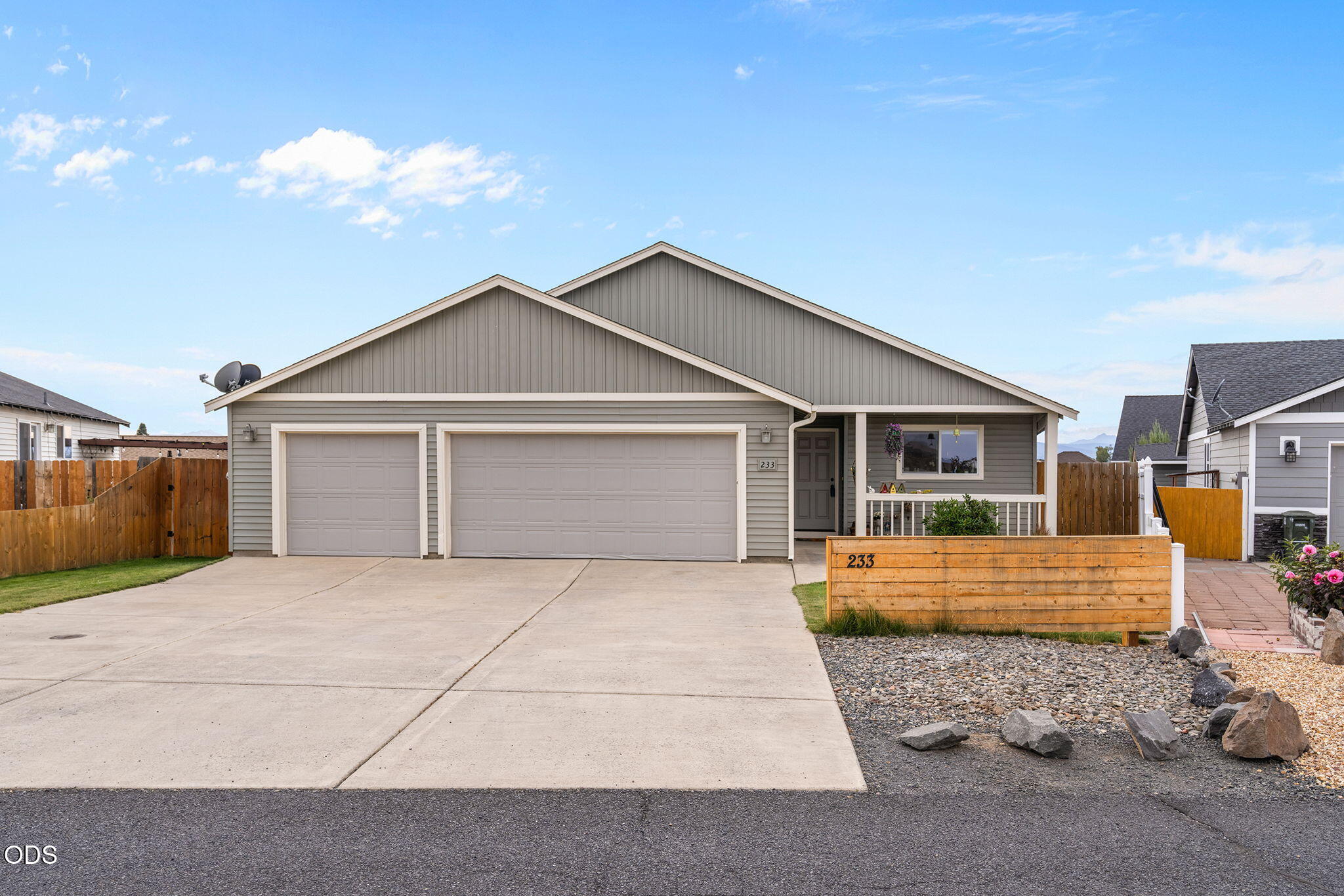 Gray single-story home with a two-car garage, broad driveway, and covered front porch.