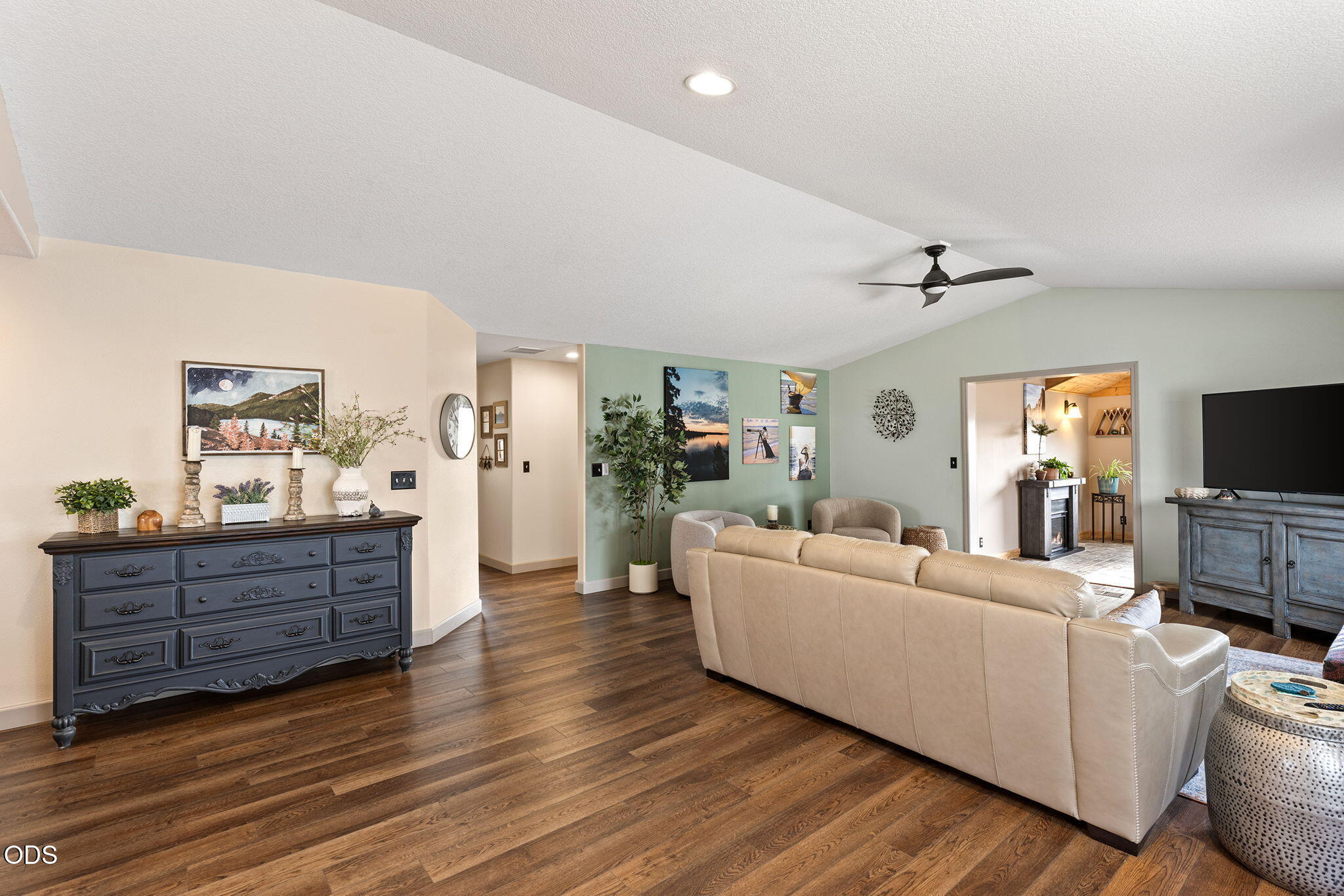 Living room with a beige sectional, vaulted ceiling, and dark wood floors.