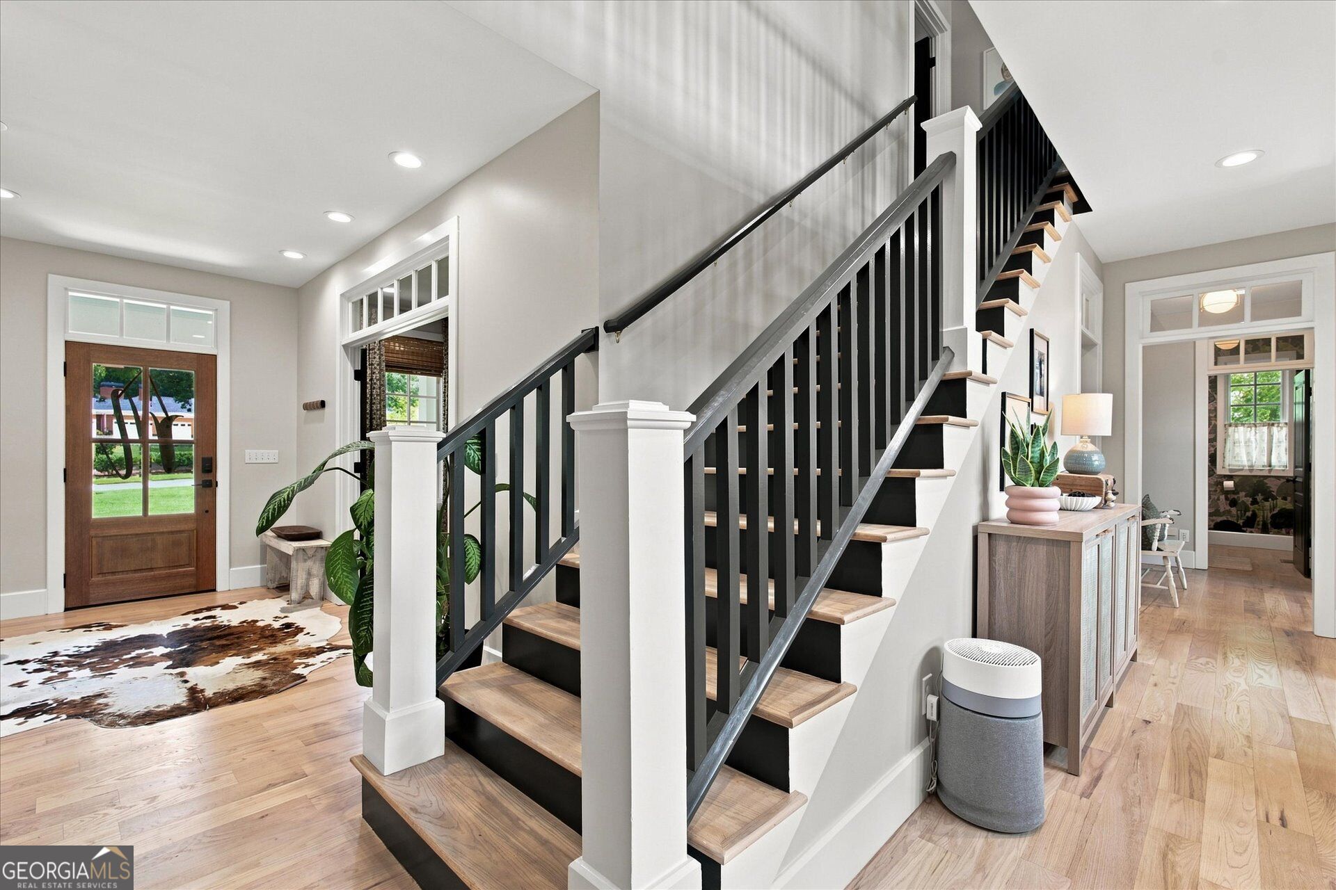 Foyer with a striking staircase of dark railings, white posts, and light wood treads.