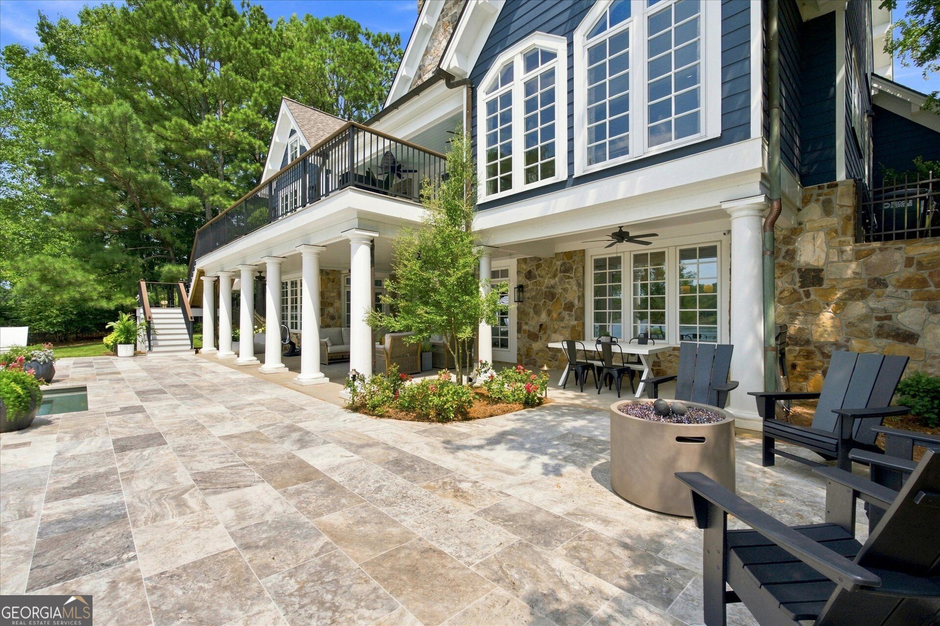 House exterior with a stone-covered patio, tiled terrace, balcony, and outdoor fire pit.