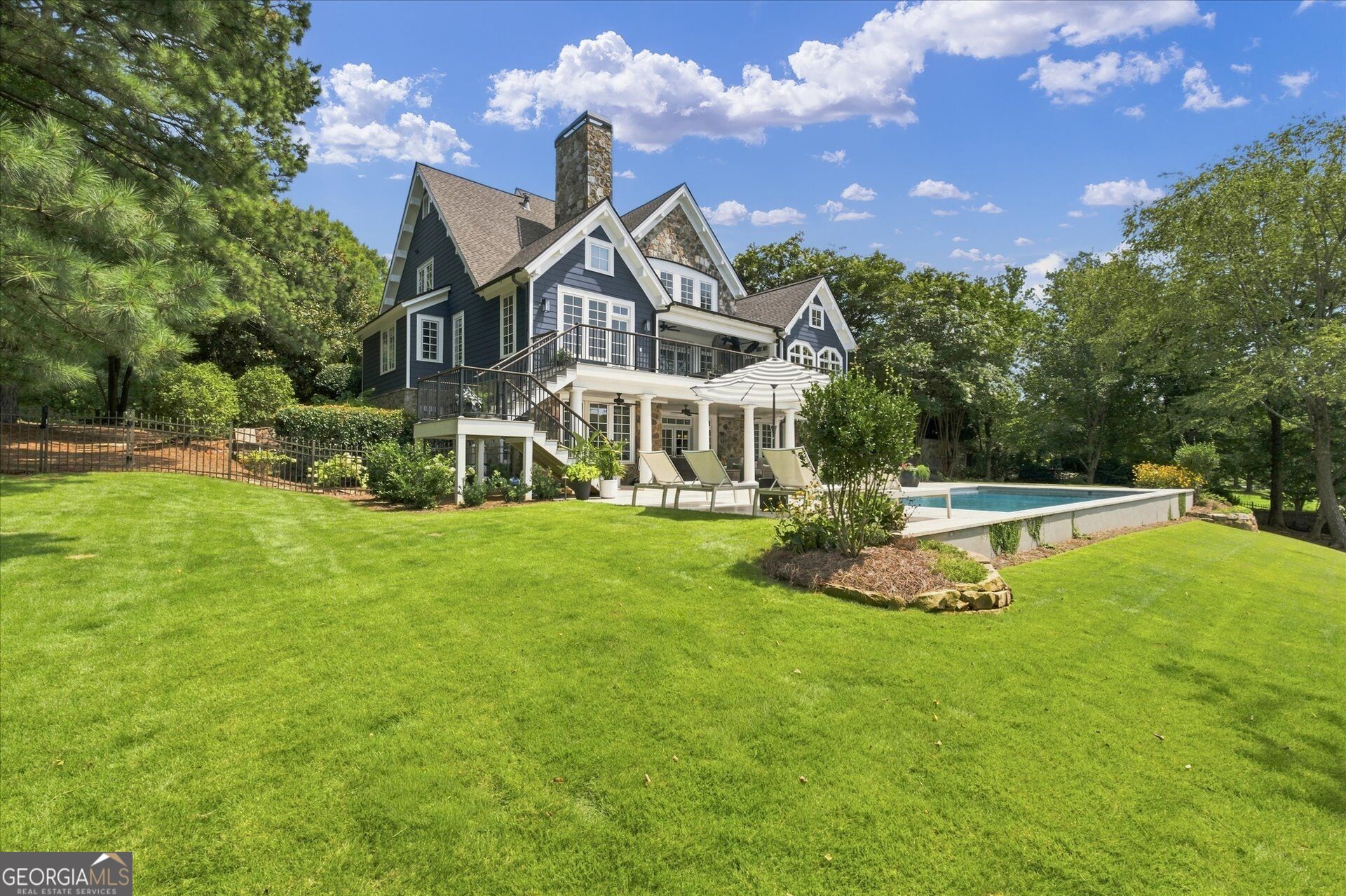 Dark blue home with a raised deck and backyard swimming pool.