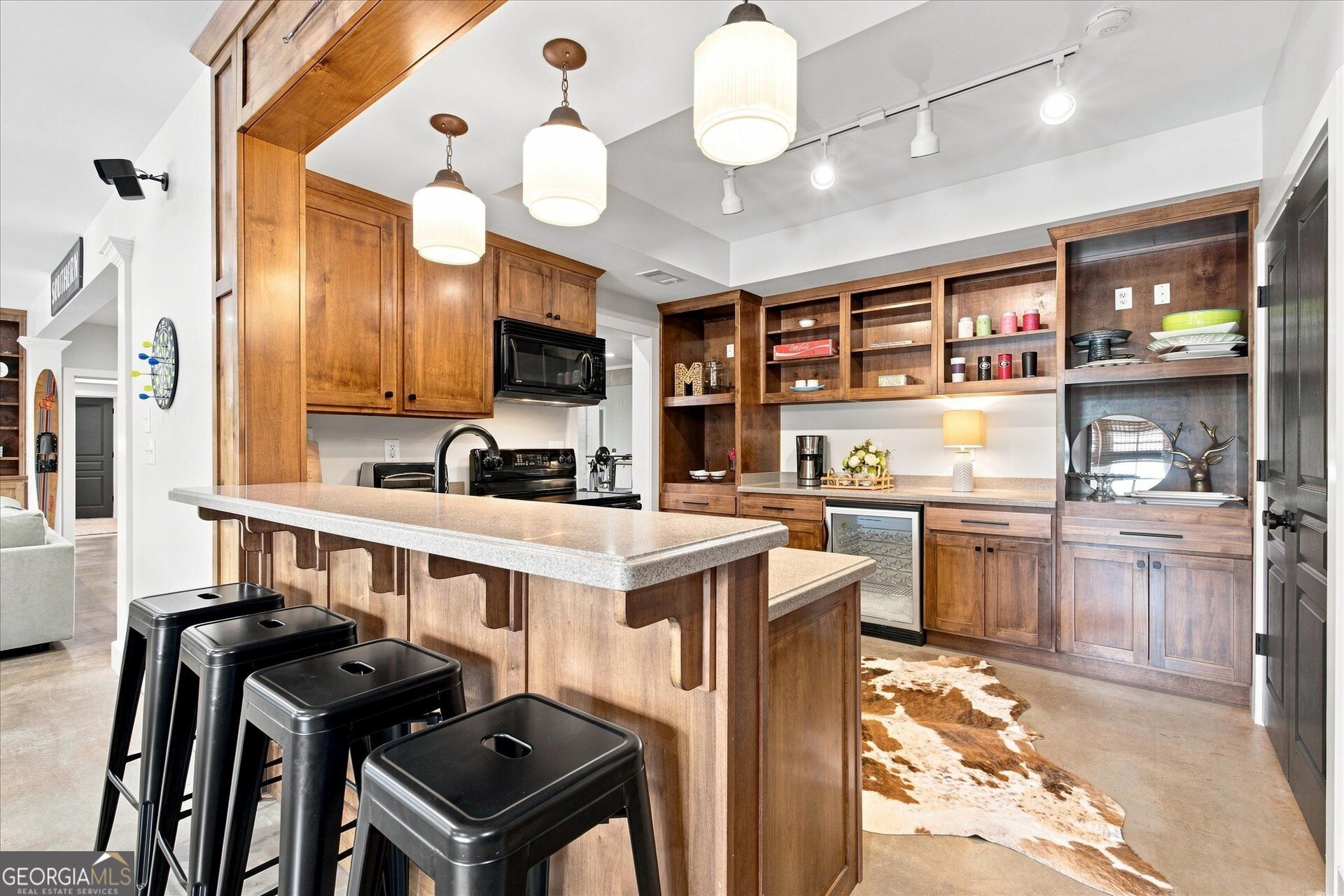 Kitchen with a large wood island, black stools, extensive cabinetry, and a built-in beverage refrigerator.