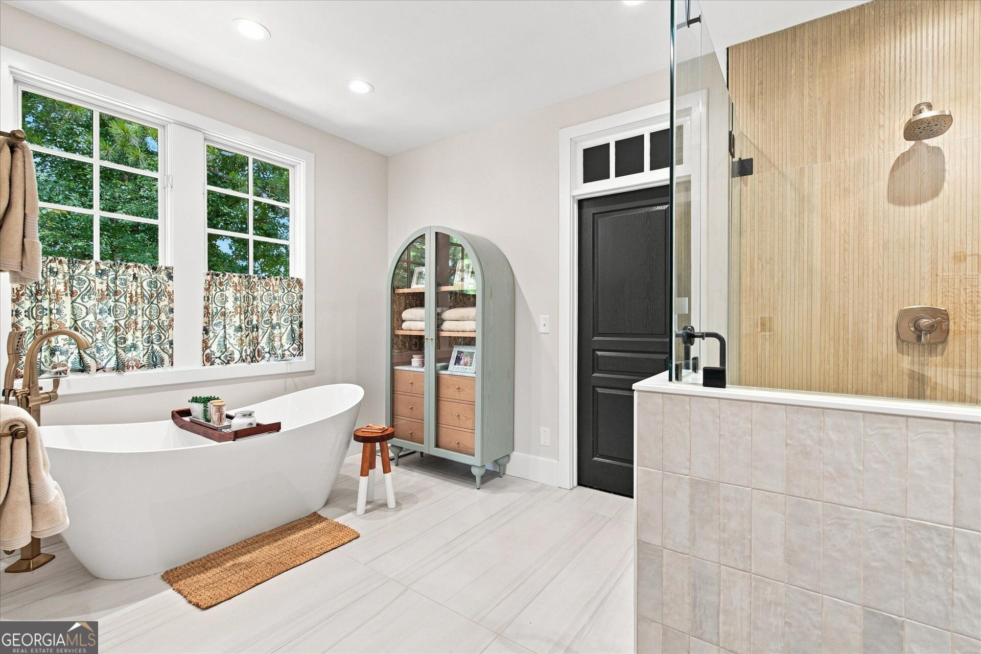 Bathroom with a freestanding soaking tub beneath large windows and a glass-enclosed shower.