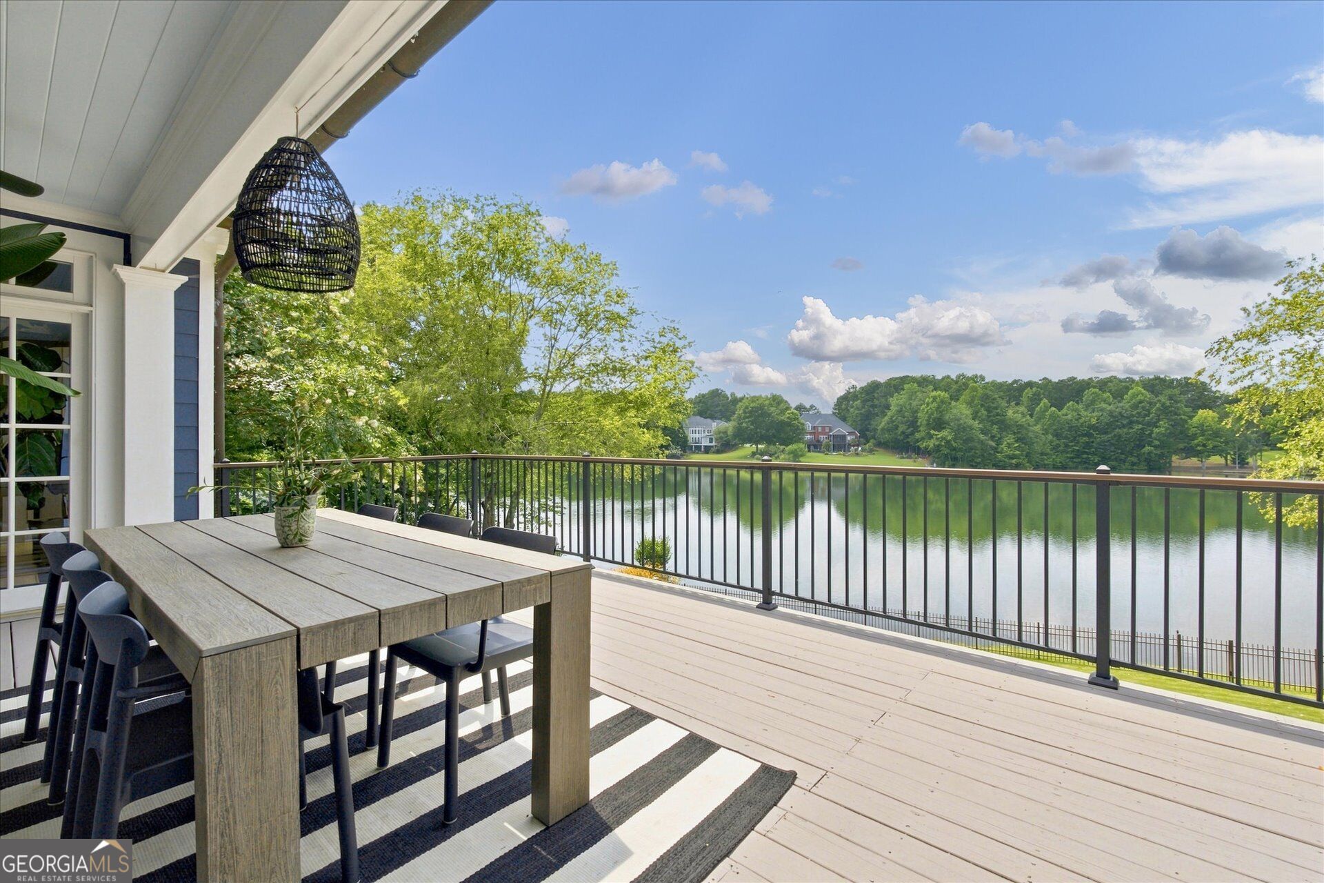 Covered lakeside deck with outdoor dining table and chairs overlooking the water.