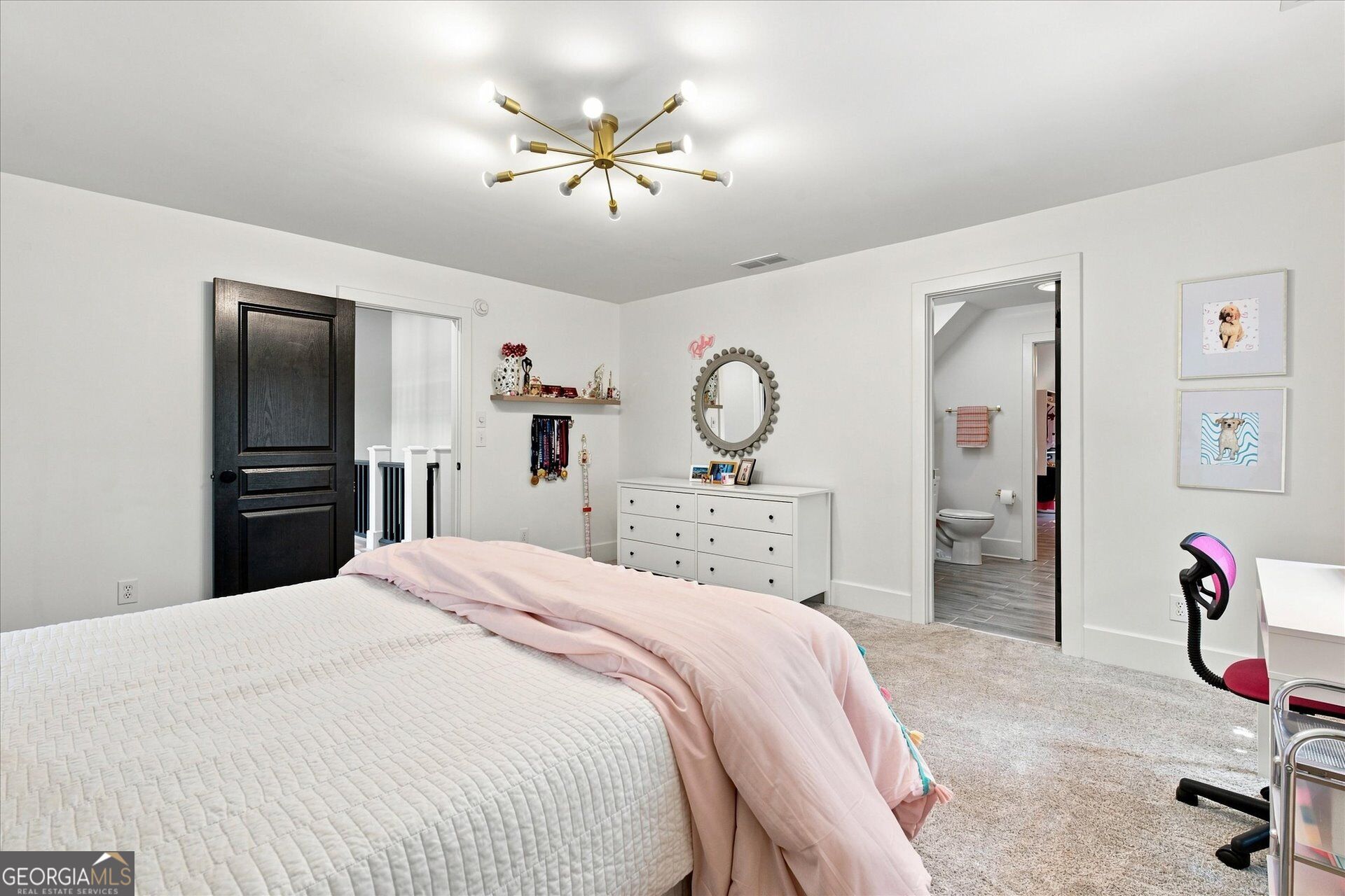 Bedroom with pale pink bedding, a white dresser, and an open doorway to the bathroom.