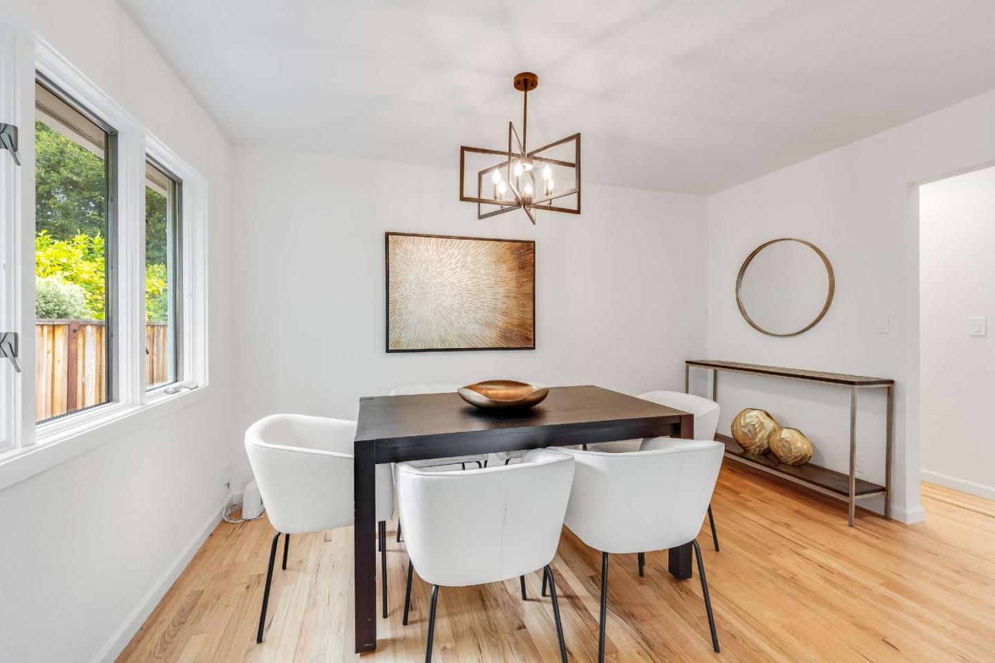 Dining room with a dark wood table, white chairs, and large windows.