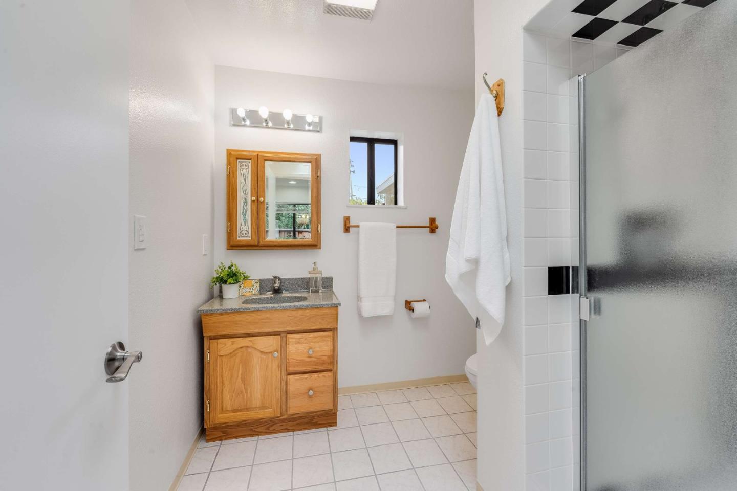 Bathroom with a wood vanity, framed mirror, and glass-enclosed shower.