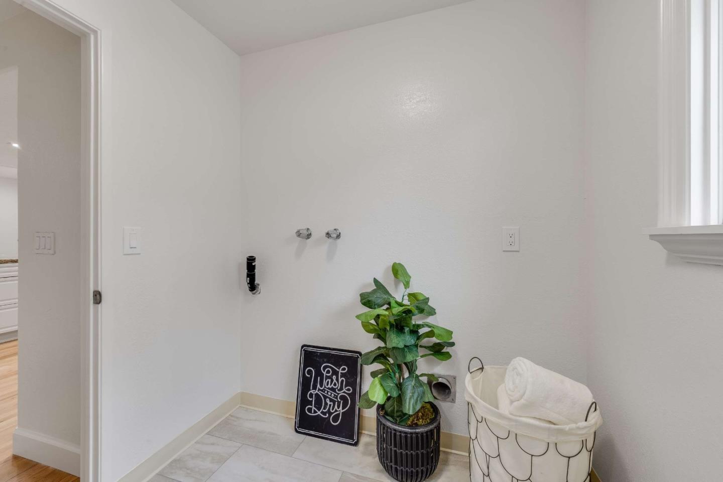 Laundry area with washer and dryer hookups, a potted plant, and a basket of towels.