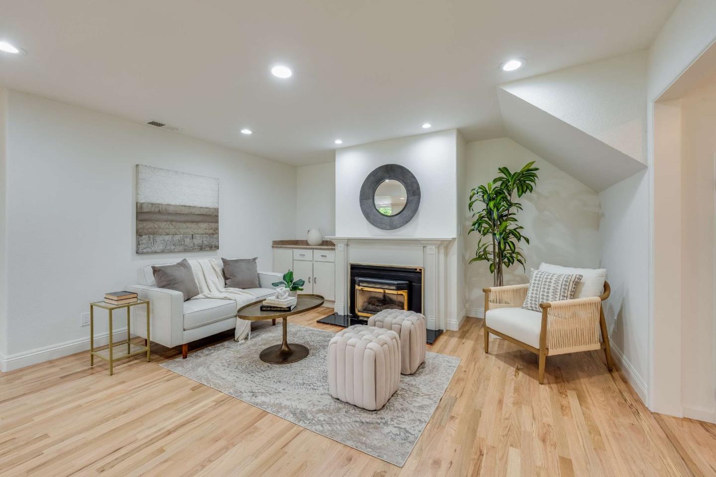 Living room with a white-mantel fireplace, pale sofa, woven armchair, and light hardwood floors.