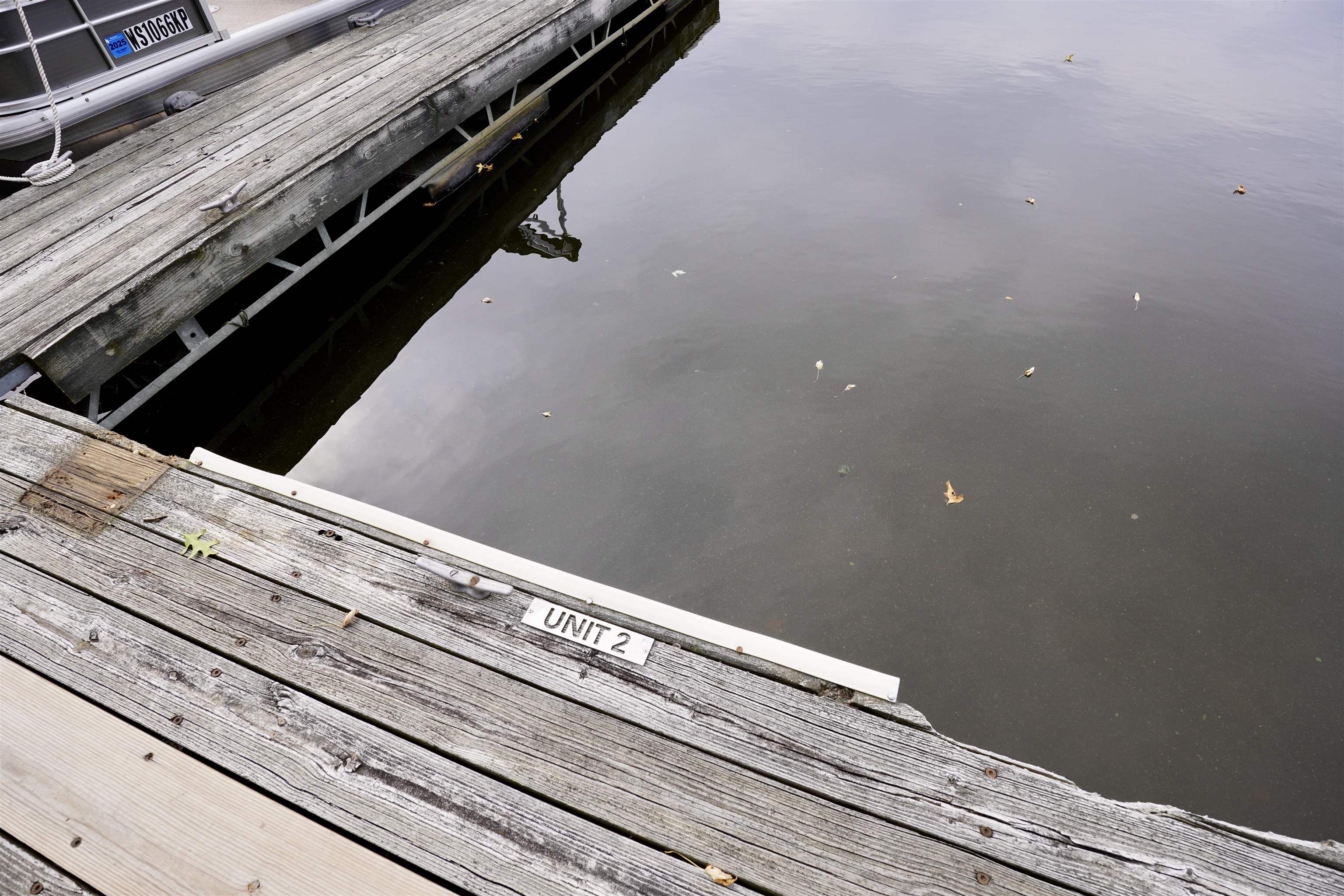 Wooden dock marked Unit 2 beside calm water, with a boat at the neighboring dock.