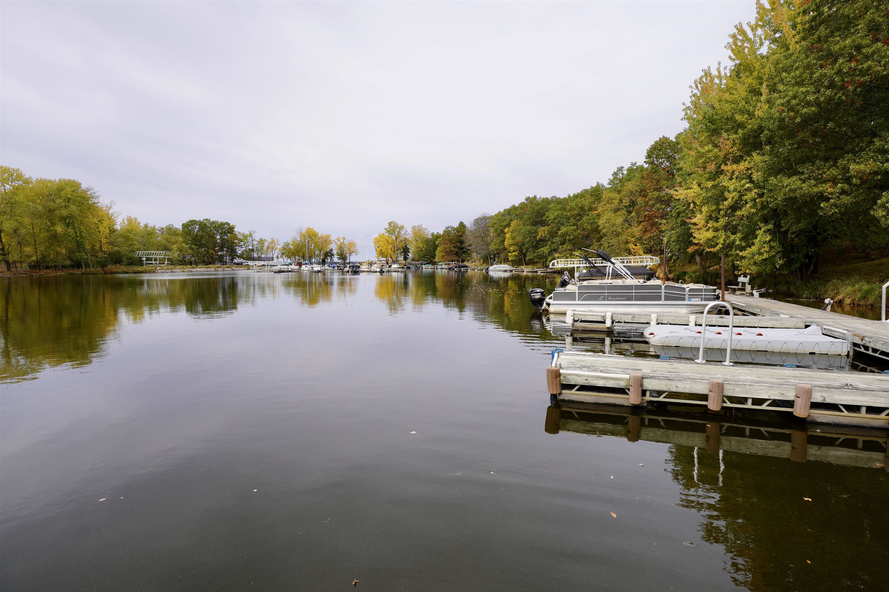 Marina with boats moored at wooden docks beside a calm, tree-lined waterway.