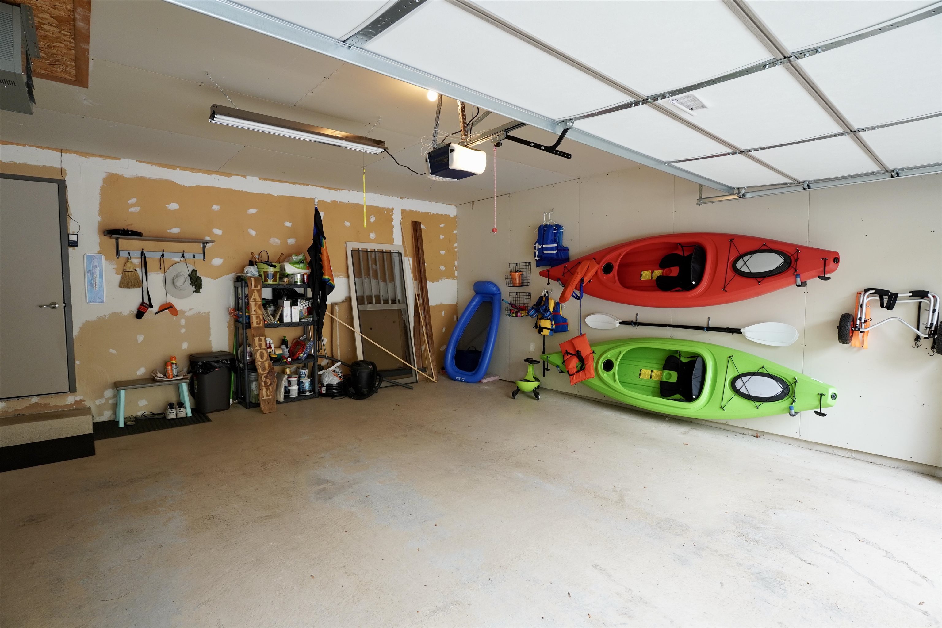 Garage with red and green kayaks mounted on the wall and storage shelves.