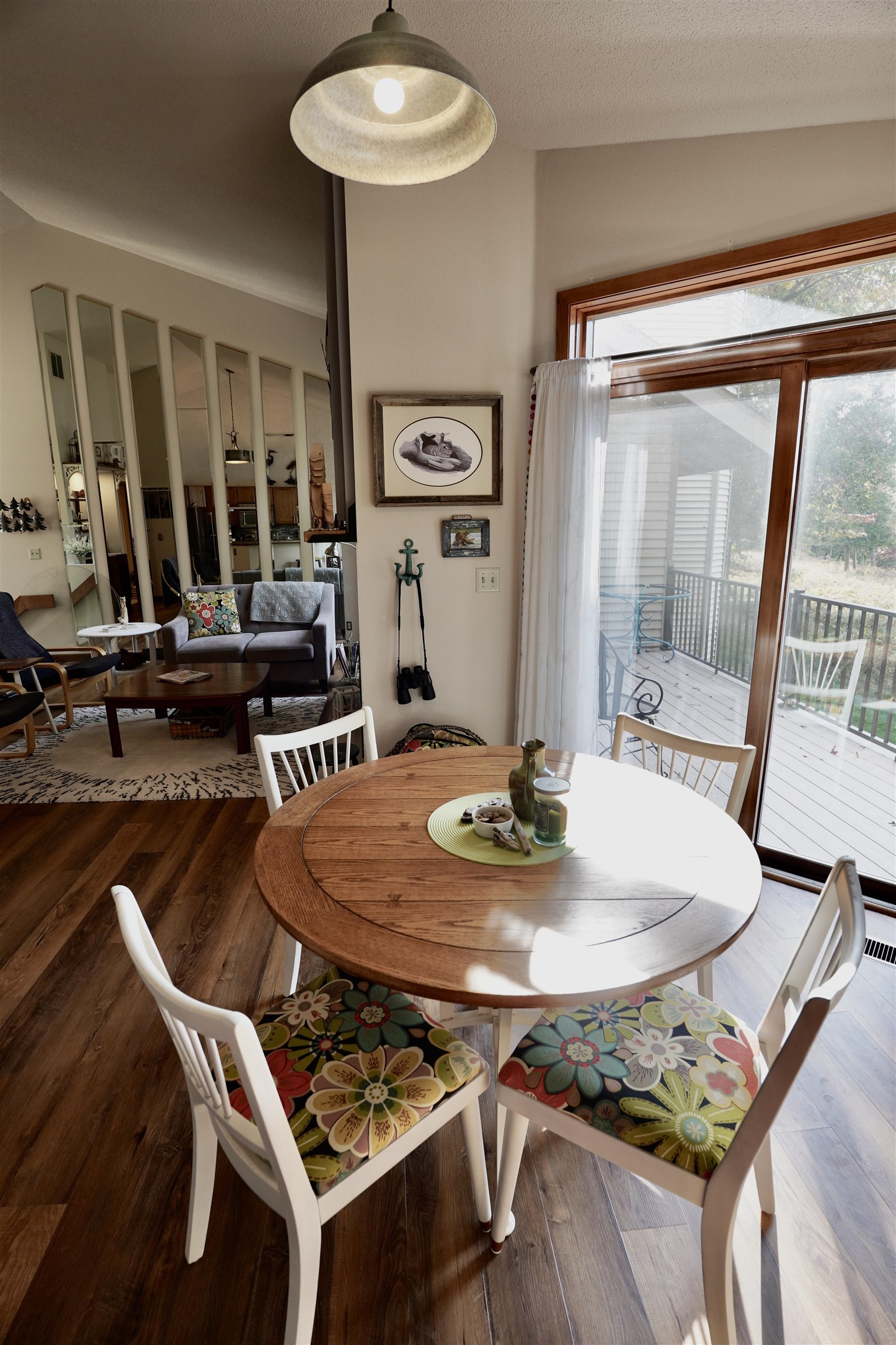 Dining area with a round wooden table, floral-cushioned chairs, and sliding doors to a deck.
