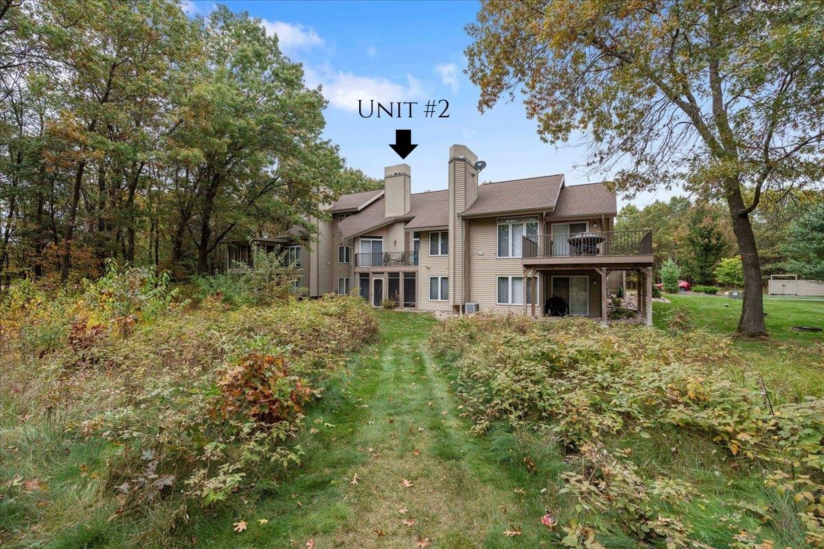 Tan multi-unit building among autumn trees, with an arrow marking Unit #2 above the deck.