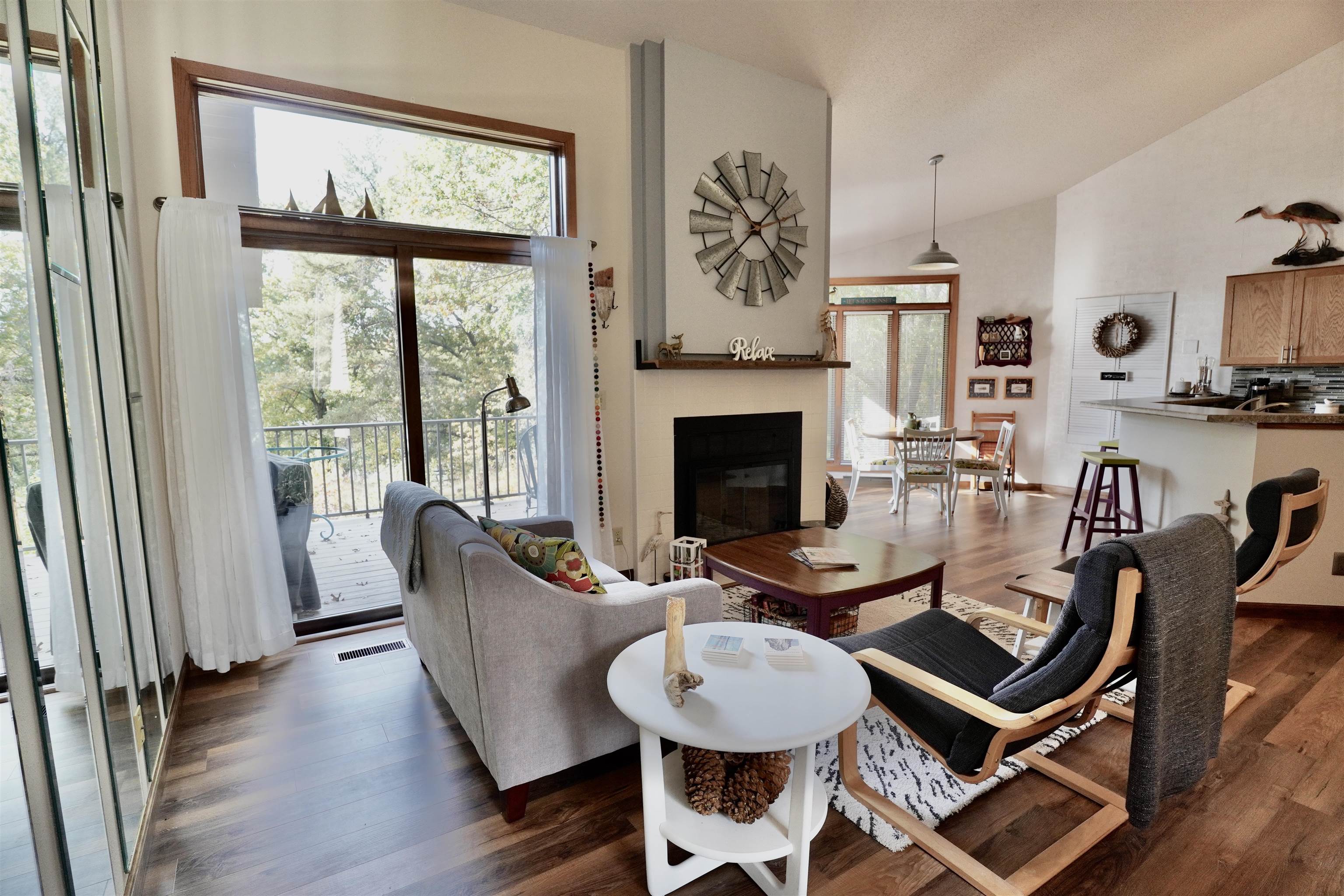 Open-plan living room with a fireplace and sliding glass doors overlooking trees.