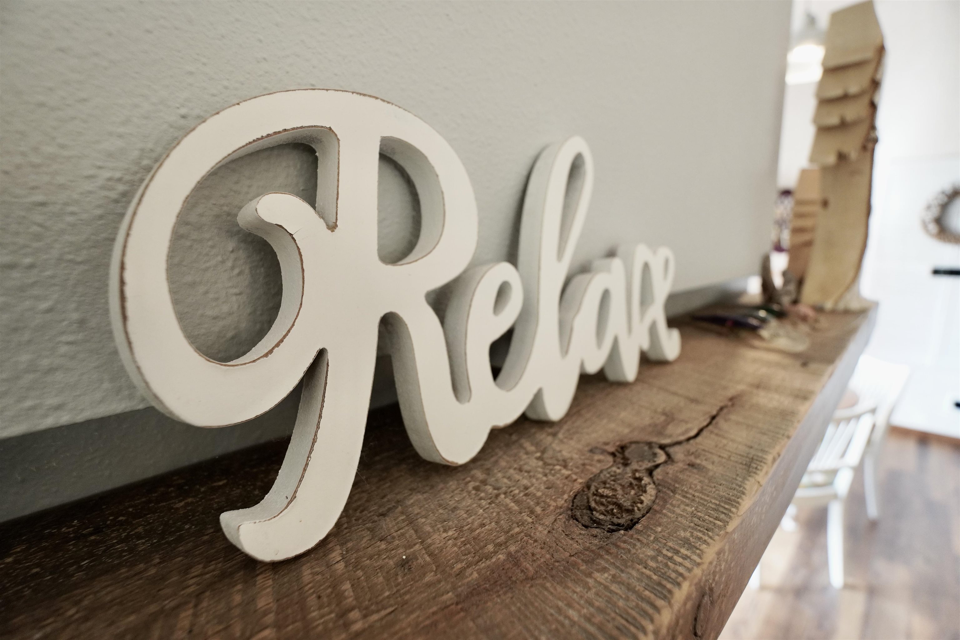 White “Relax” sign on a rustic wooden shelf inside the home.