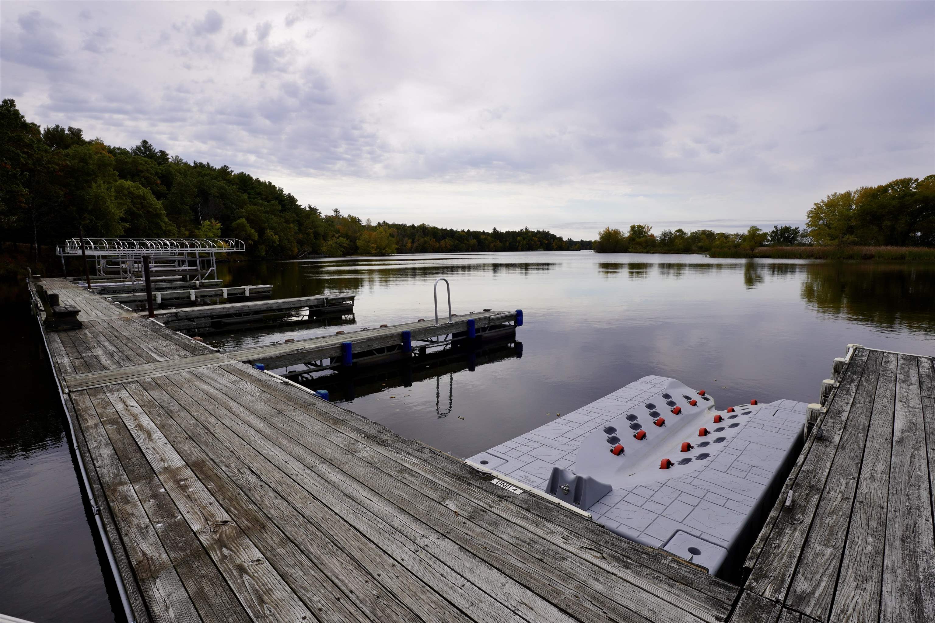 Wooden docks and a floating dock extend into a calm lake bordered by autumn trees.