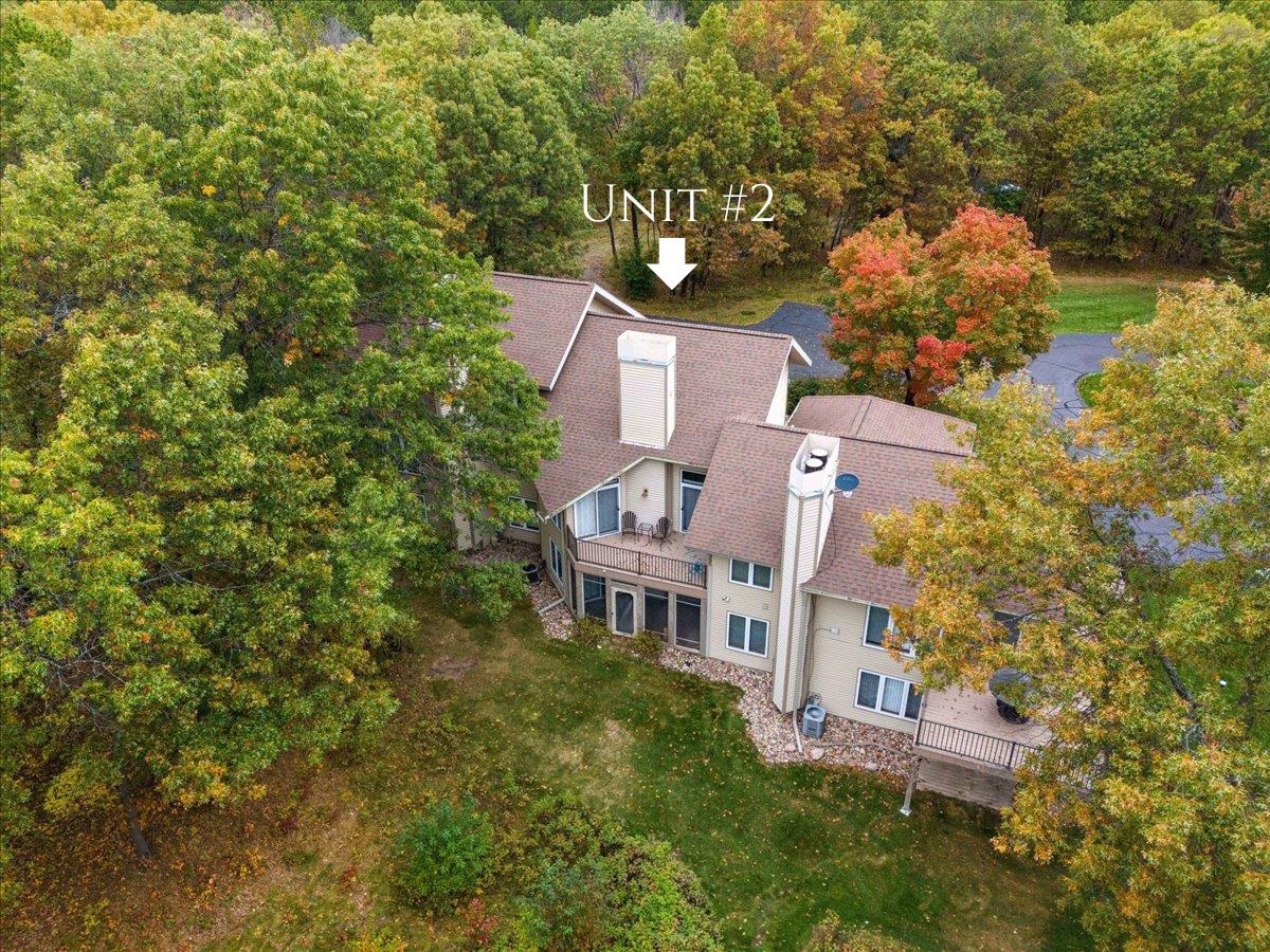 Aerial view of Unit 2 amid autumn trees, showing the building’s balconies and paved parking area.