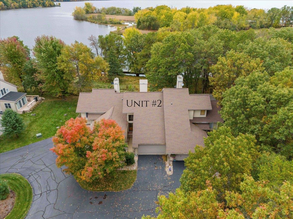 Aerial view of Unit 2 beside a lake, with autumn foliage surrounding the building.