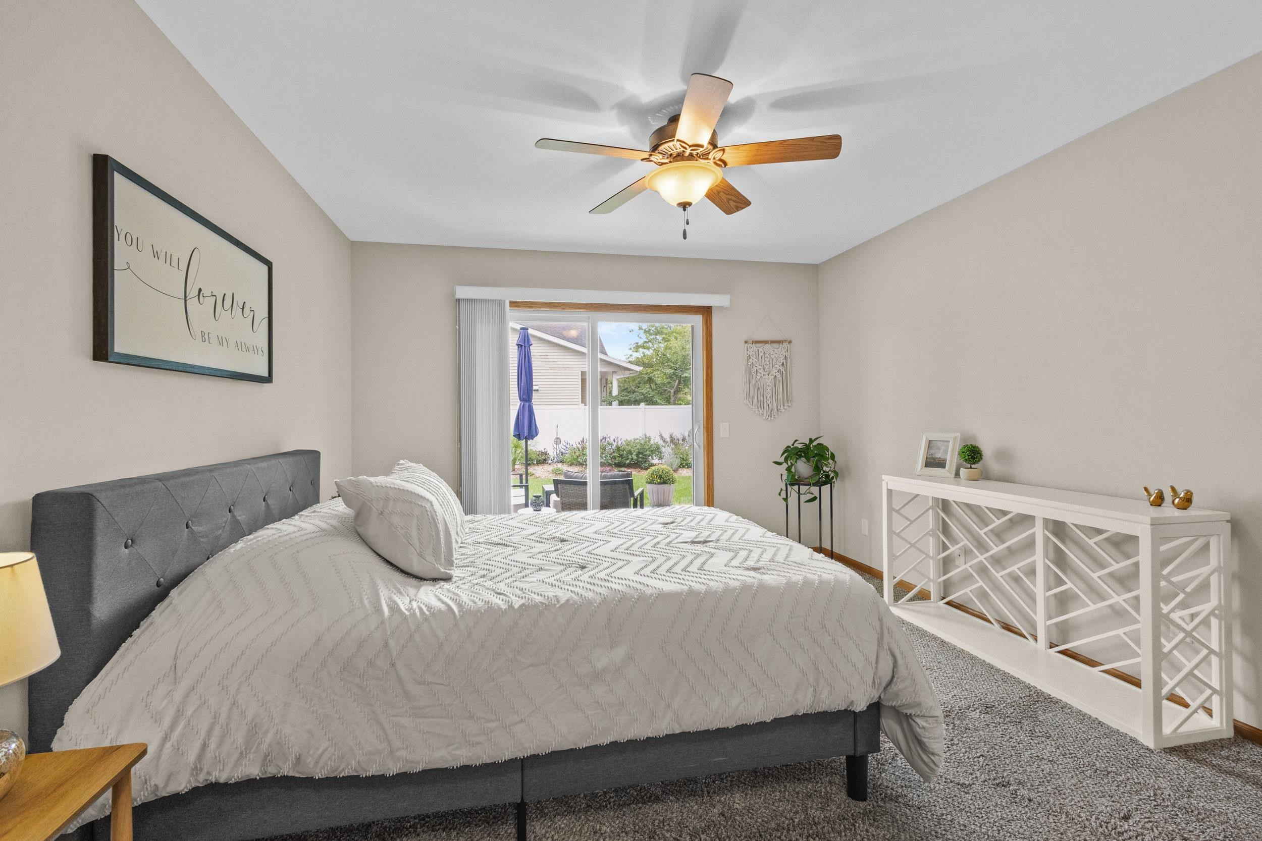 Bedroom with a gray upholstered bed, white bedding, and sliding glass doors to the yard.
