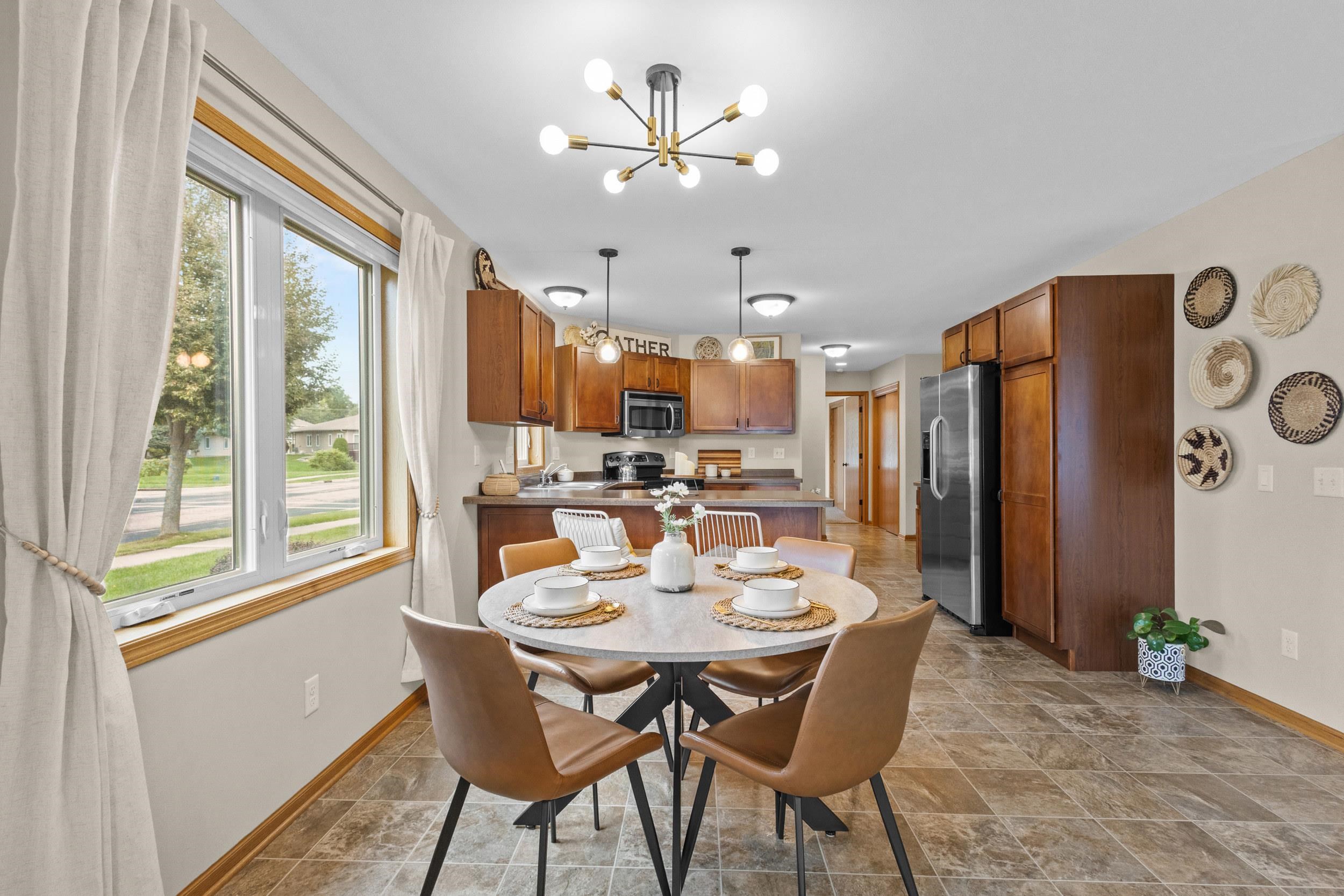 Kitchen and dining area with warm wood cabinets, stainless steel appliances, and a set round table by the window.
