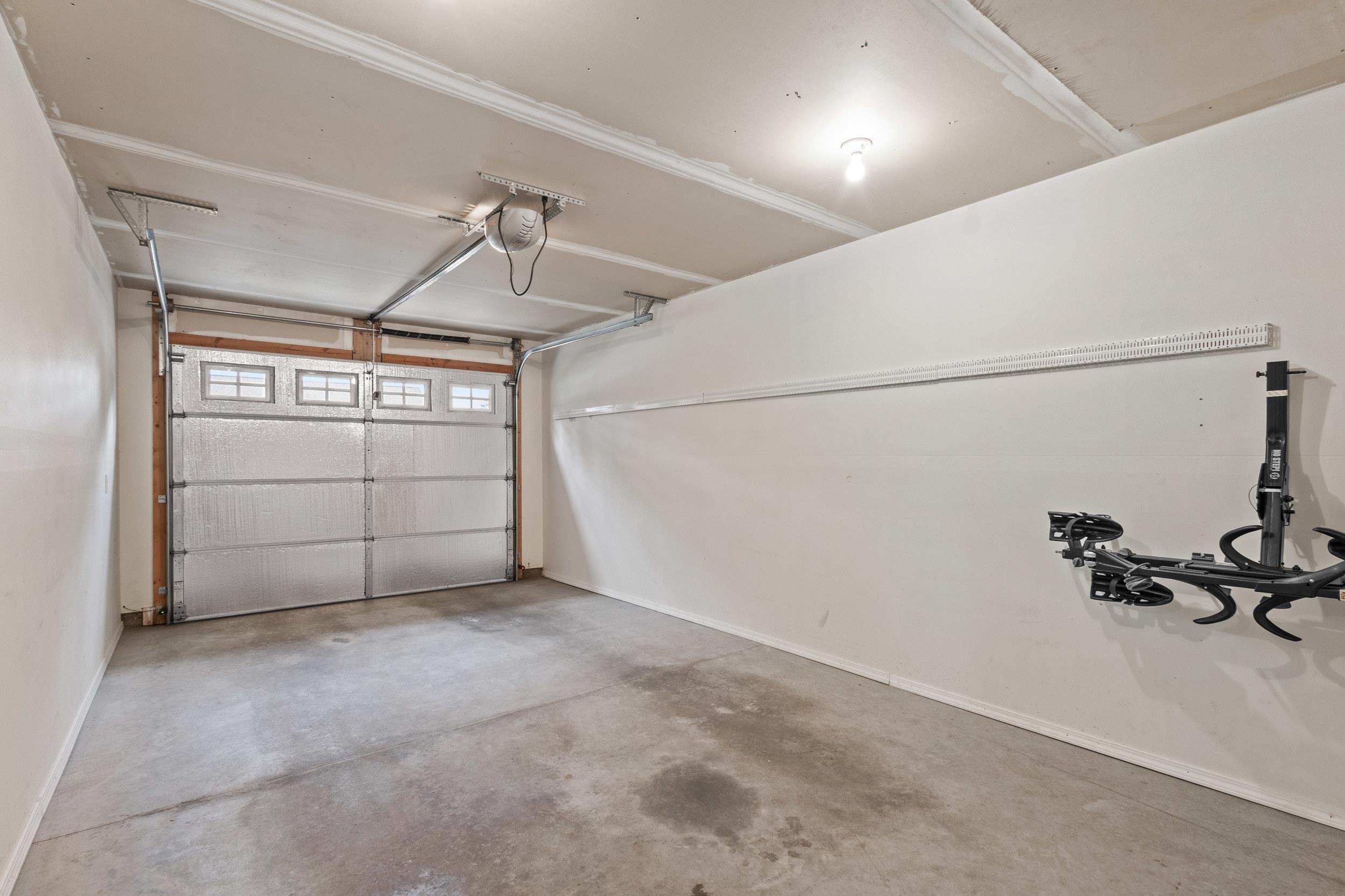 Garage with an insulated overhead door, concrete floor, and wall-mounted bike rack.