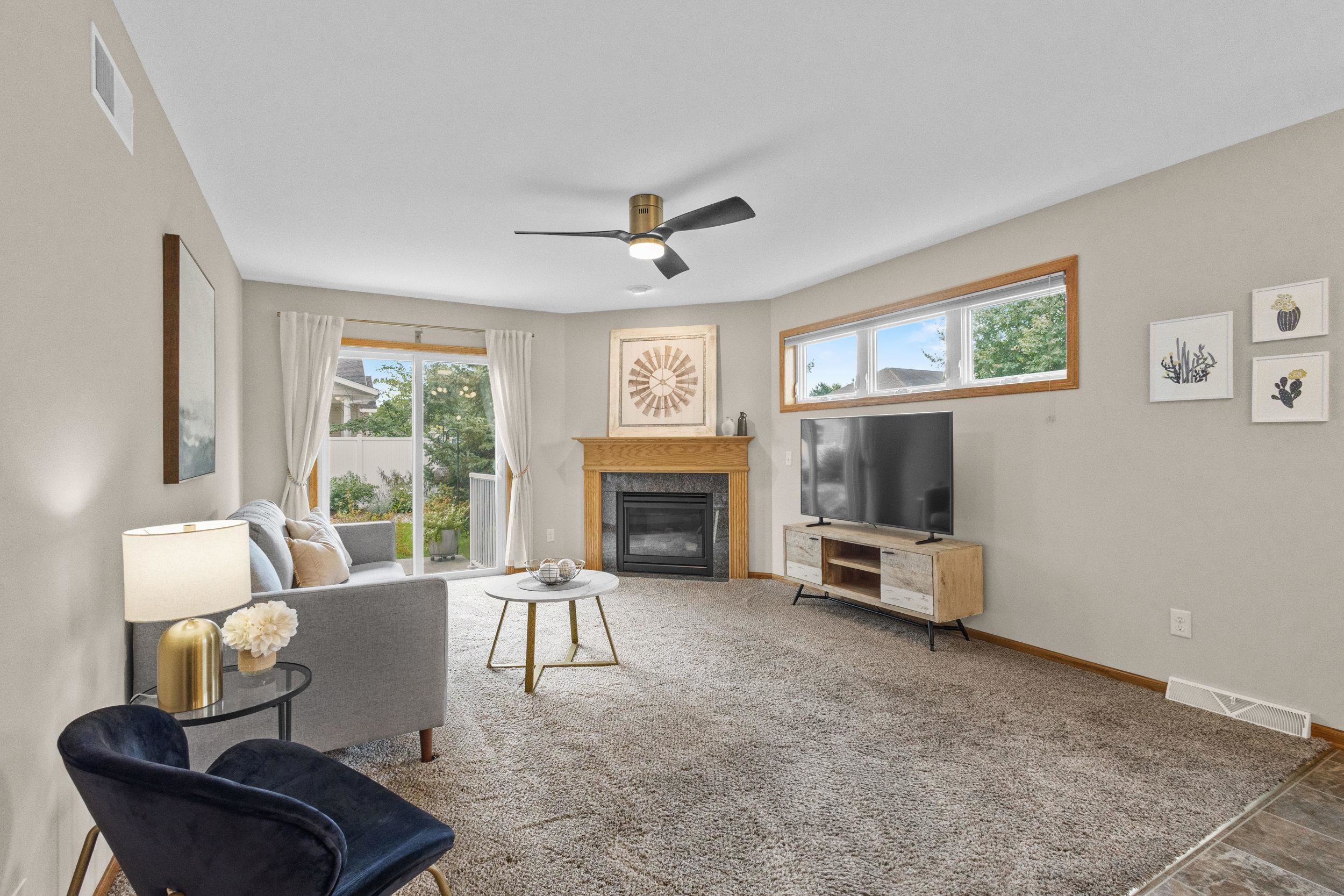 Living room with a wood-mantel fireplace, carpet, and windows overlooking the yard.