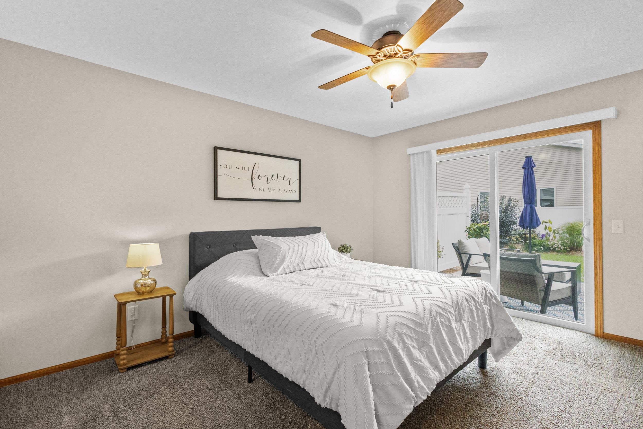Bedroom with a white-covered bed and sliding glass doors opening to a furnished patio.